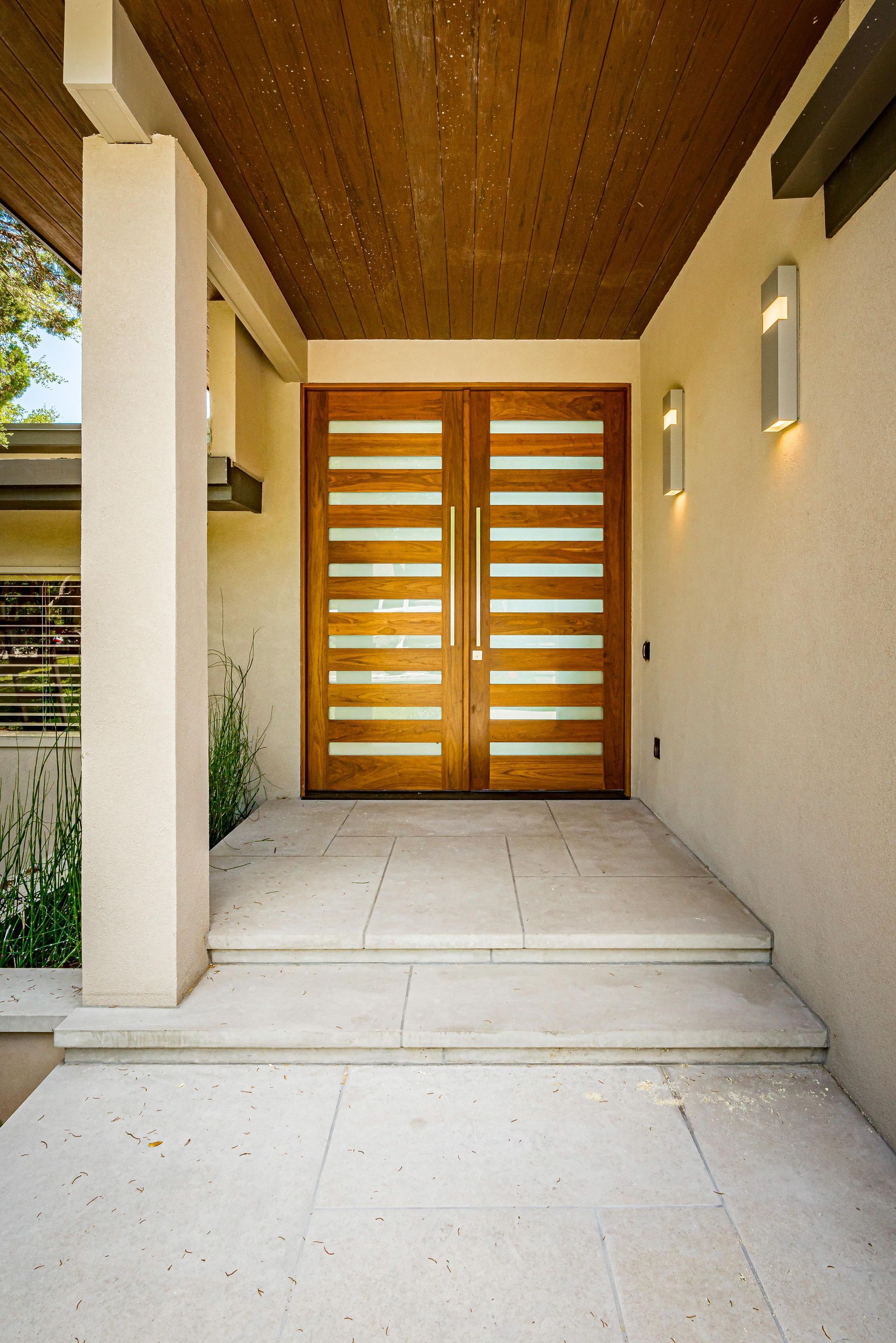 Beige stucco exterior with wooden double doors and horizontal glass panels.