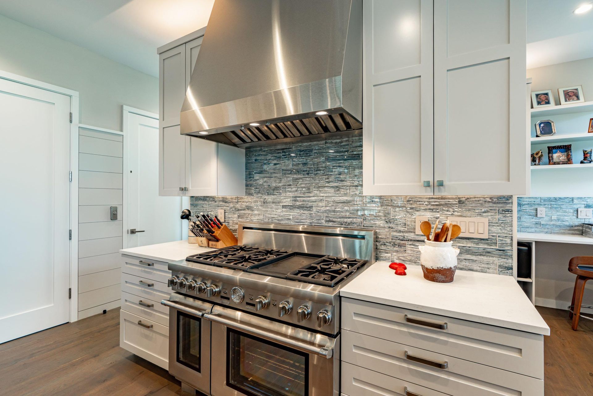 Modern kitchen with stainless steel appliances, white cabinets, and a gray tile backsplash.