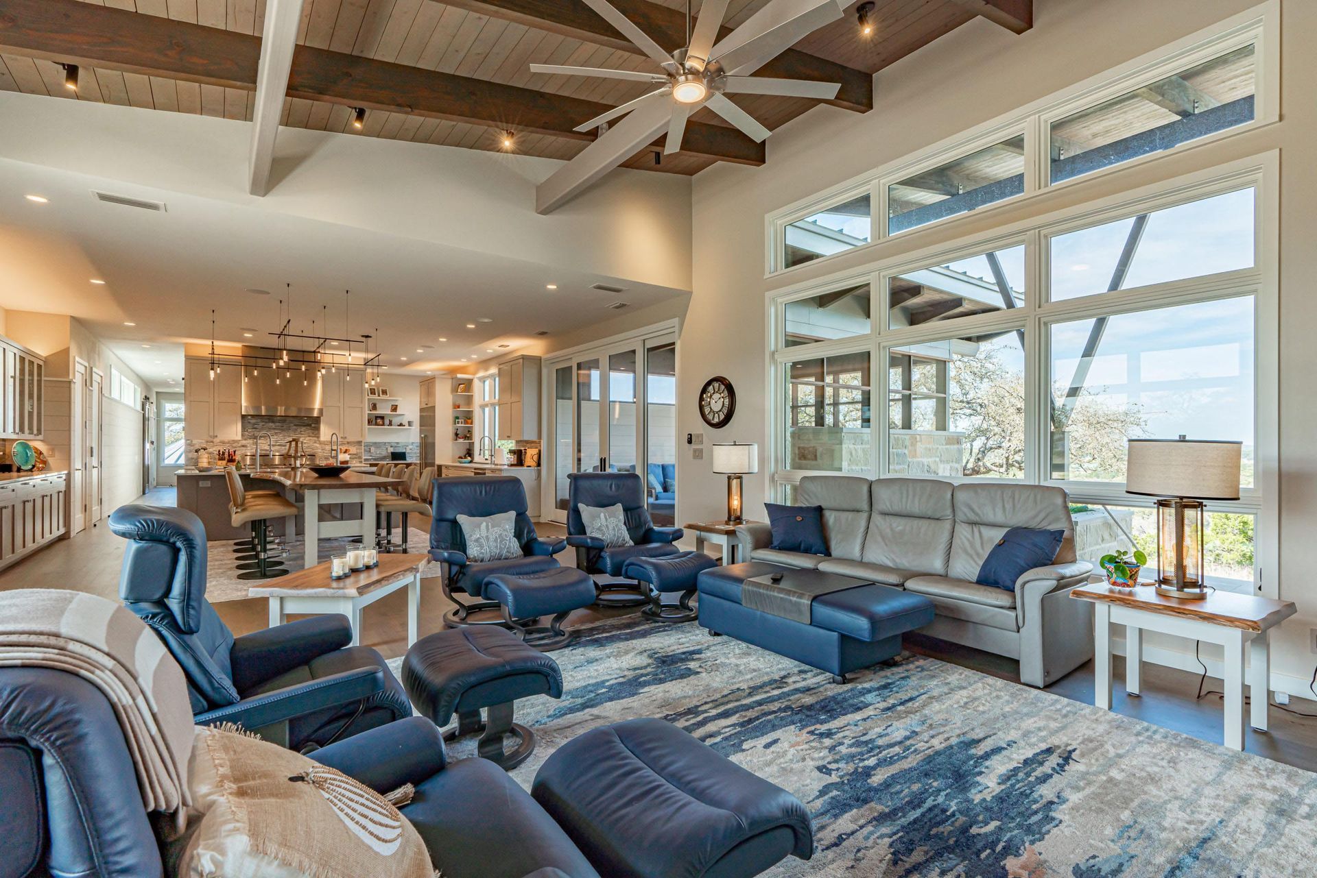 Spacious living room with high ceilings, large windows, and blue and gray furniture.
