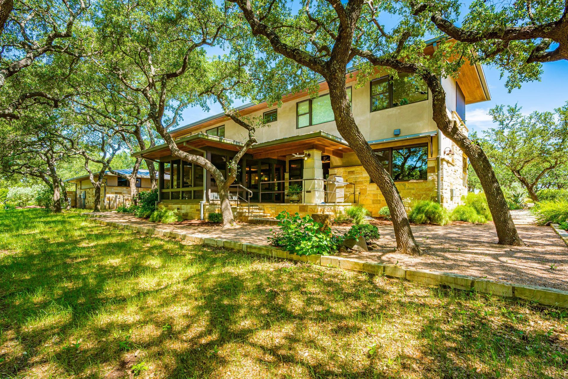 Two-story home with porch, shaded by trees, in a grassy setting.