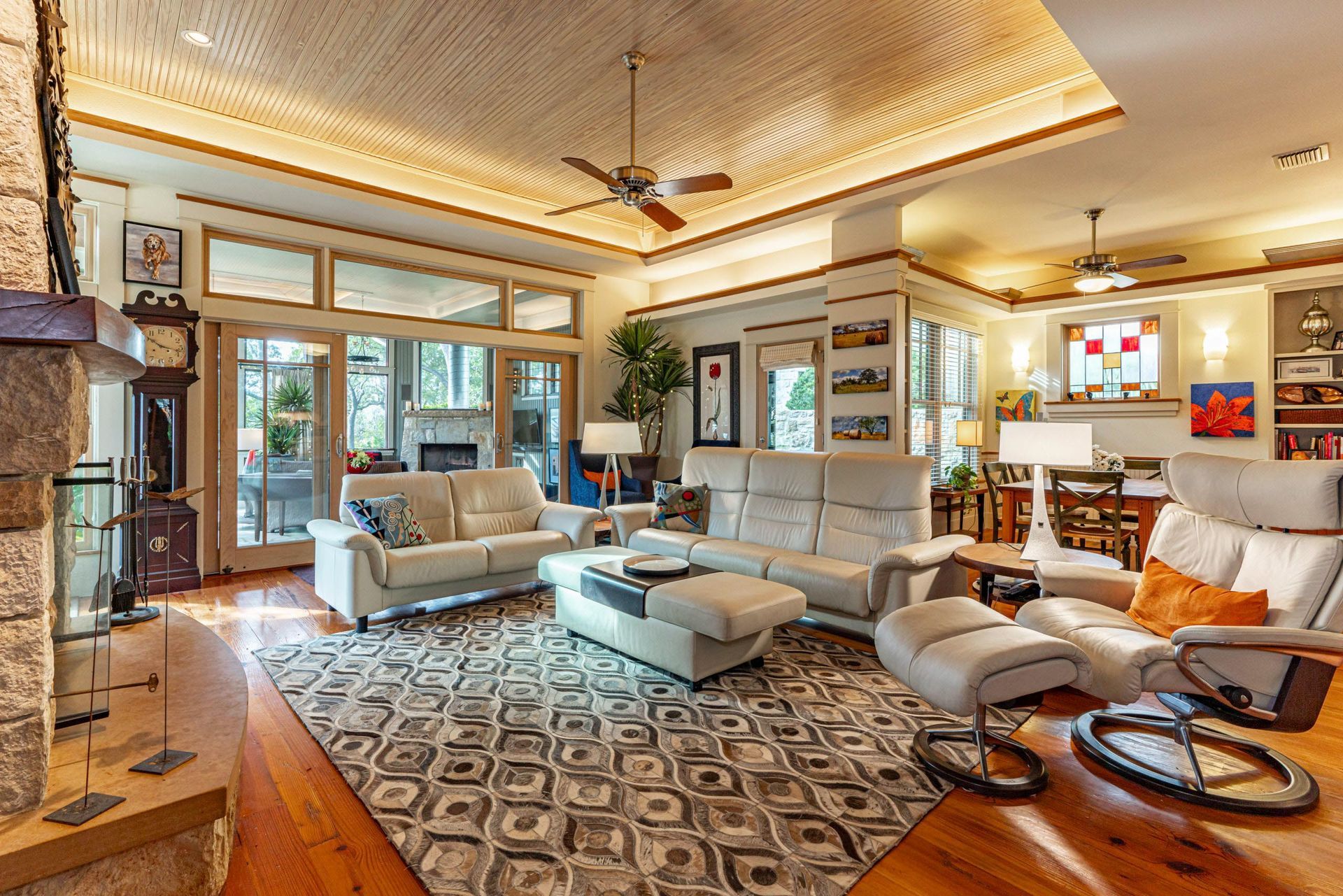 Living room with light-colored modern furniture, fireplace, and large windows leading to a patio.