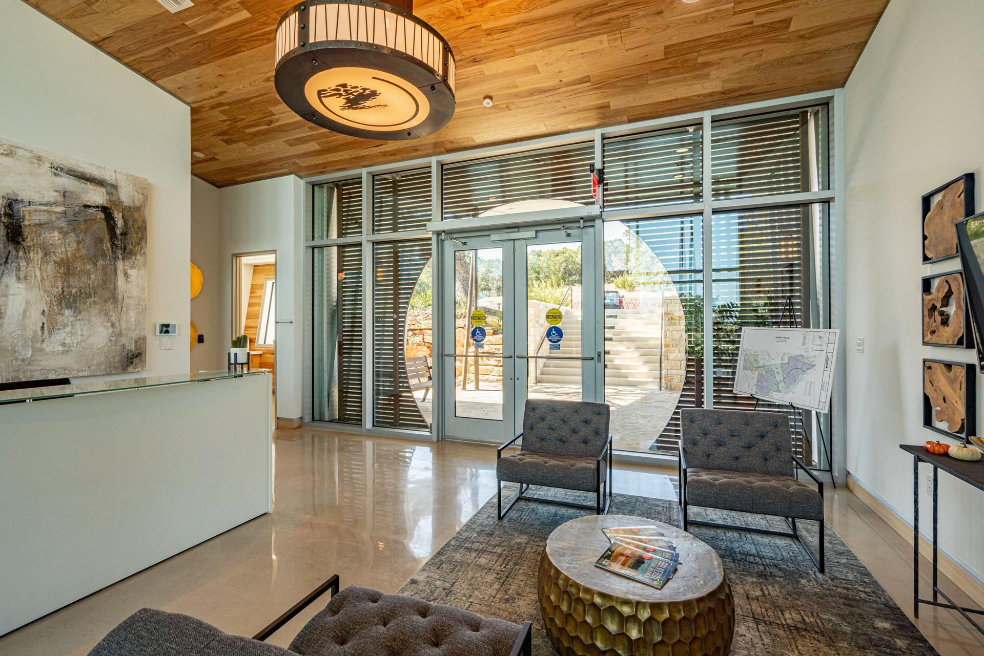 Reception area with light-colored walls, wood ceiling, large windows, chairs, and coffee table.