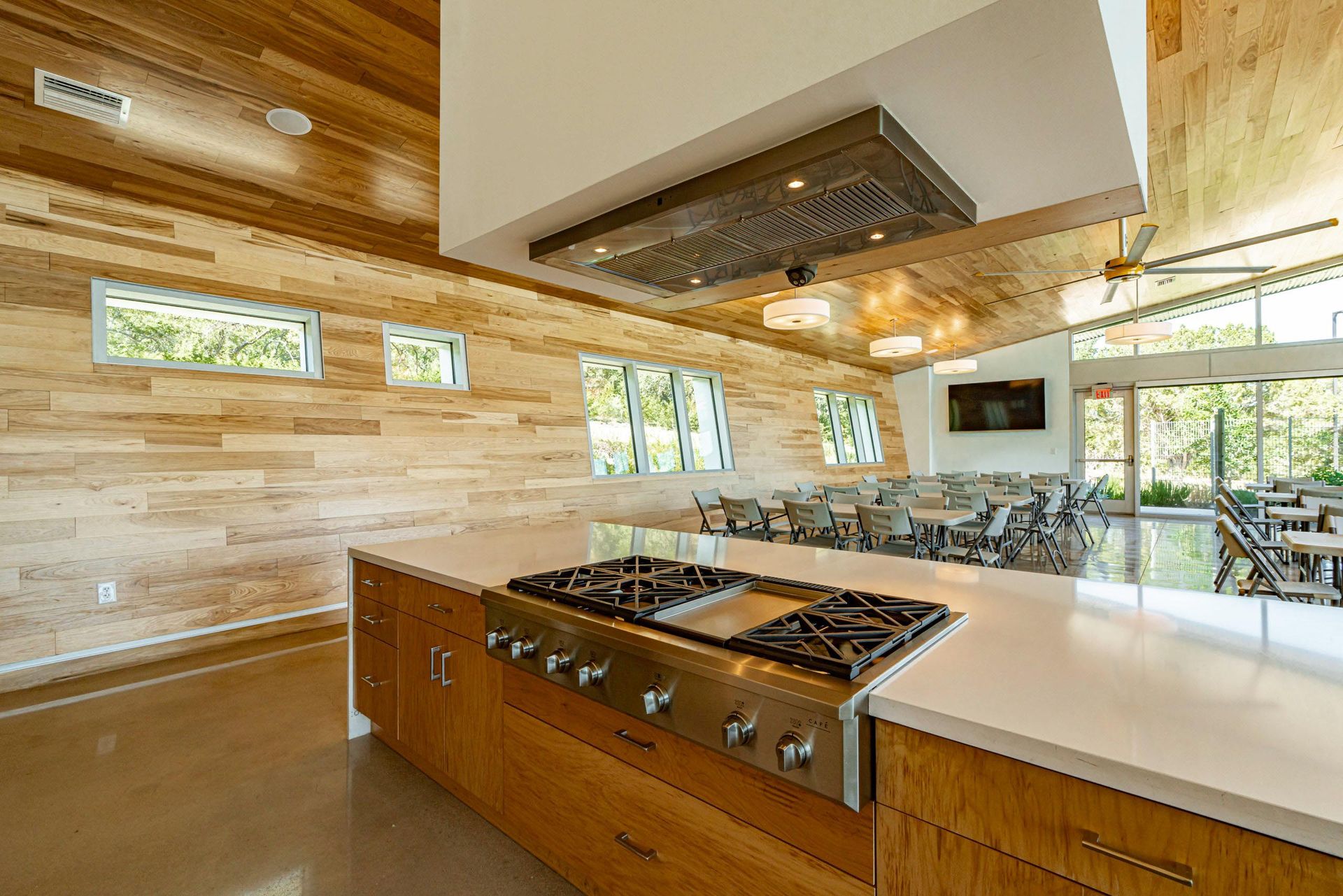 Kitchen with a large island, stainless steel range, wooden cabinets, and a dining area visible in the background.