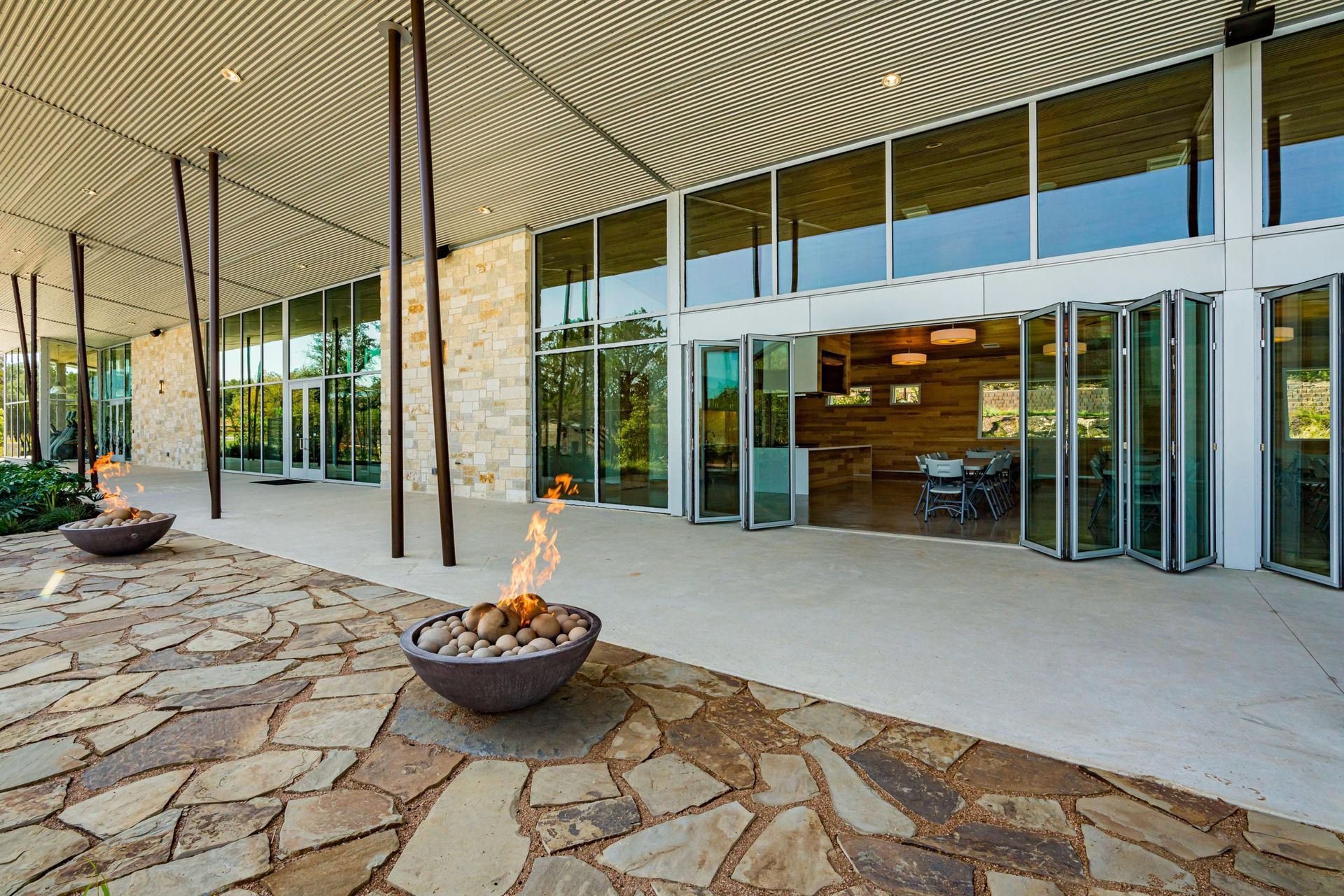 Covered patio with stacked stone flooring, fire pits, glass doors, and a modern ceiling.