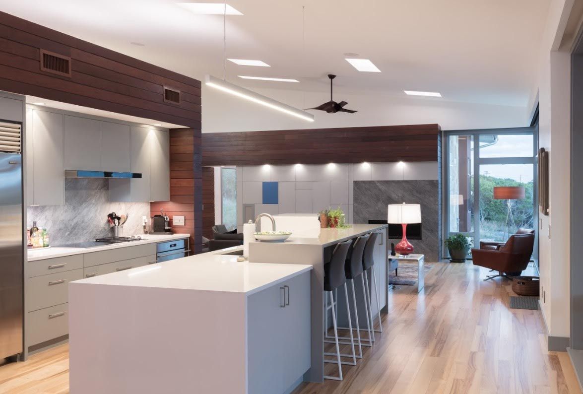 Modern kitchen with large island, stainless steel appliances, and wooden accent wall.