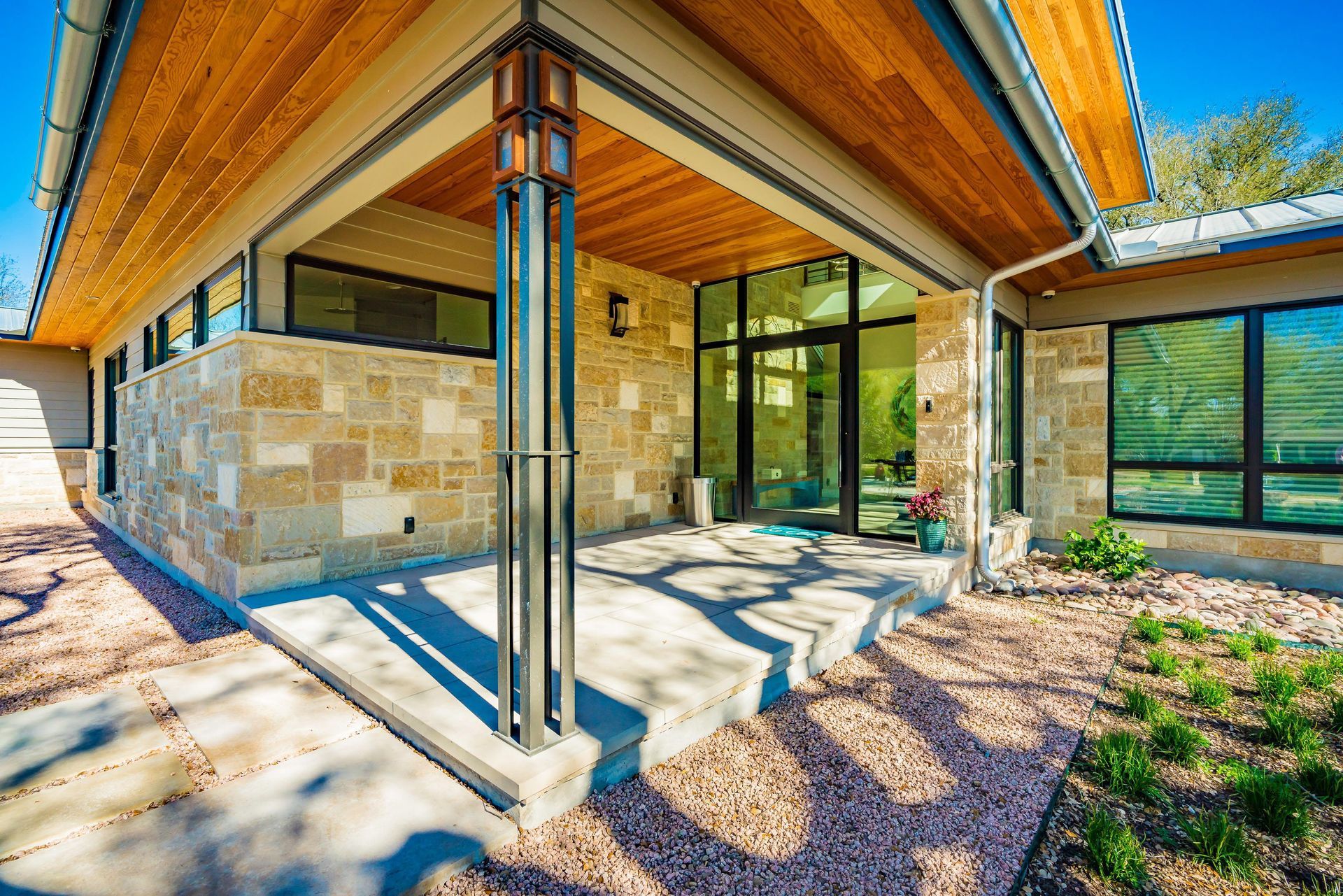 Modern home exterior with stone and wood accents; glass door and windows.
