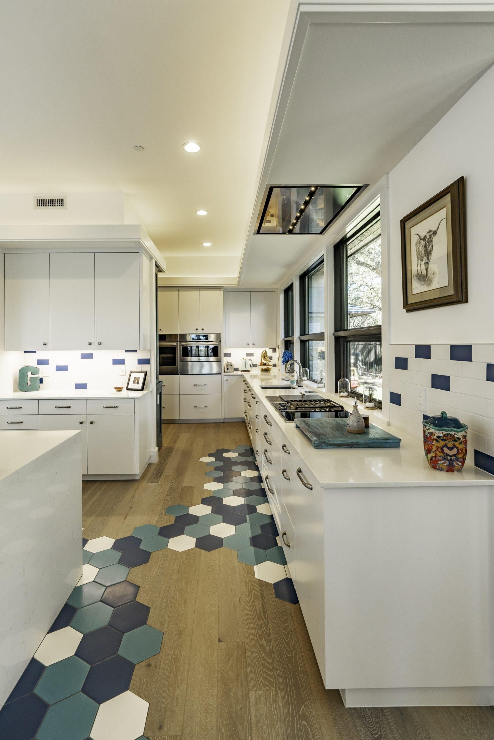 Modern white kitchen with blue hexagon tile floor and backsplash.