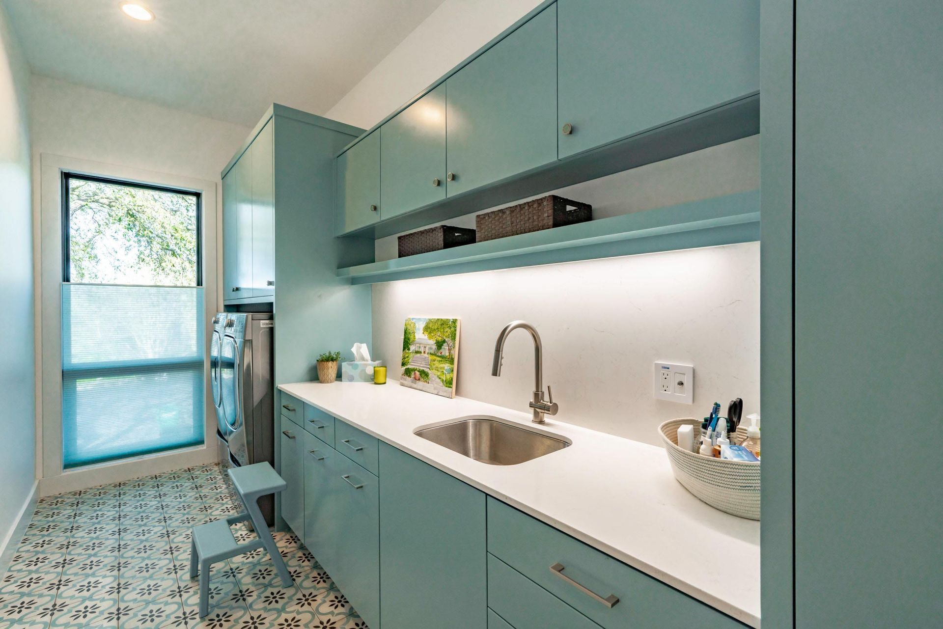 Laundry room with light blue cabinets, white countertop, and patterned floor tile.