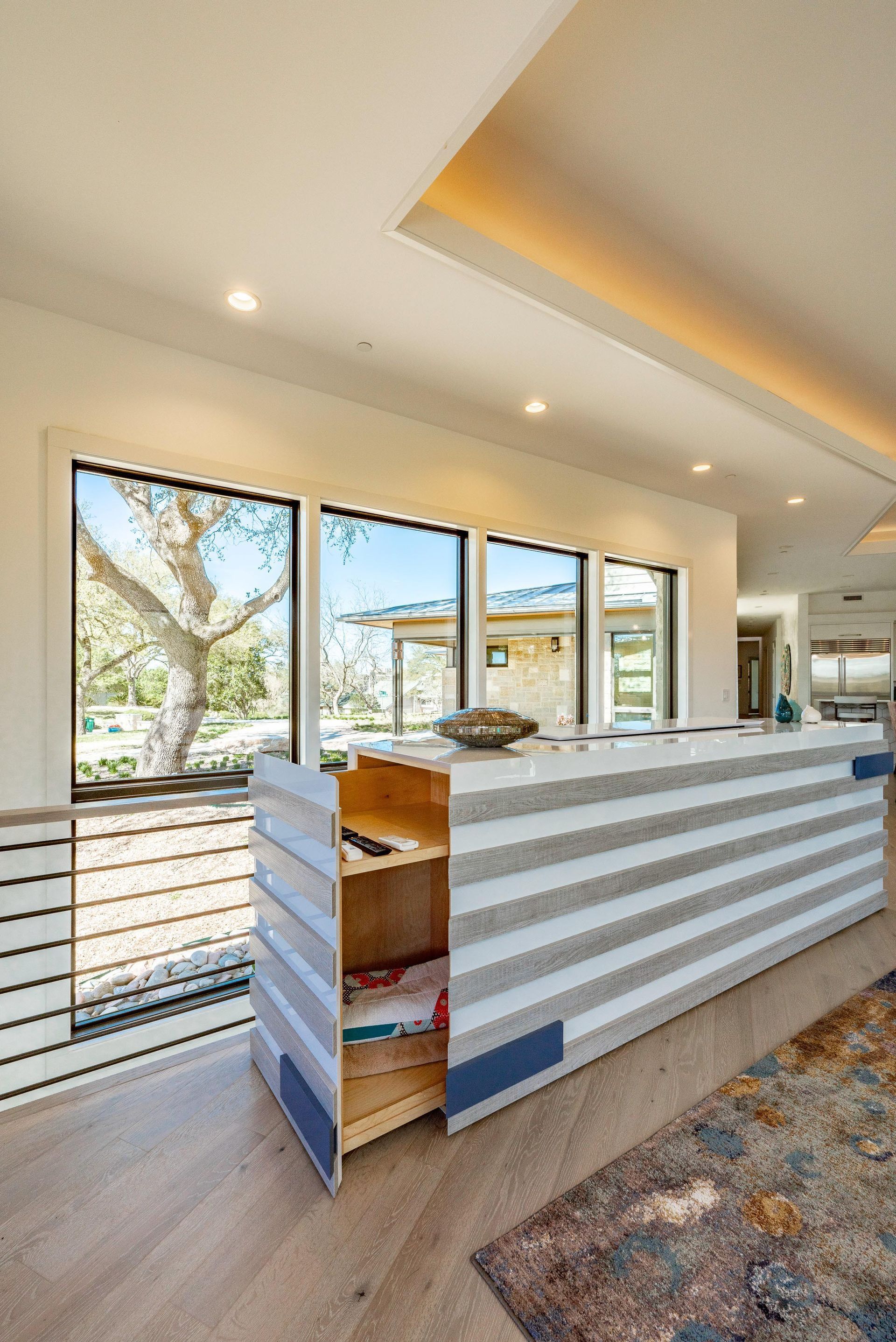 Modern kitchen island with striped gray and white design, next to a large window.