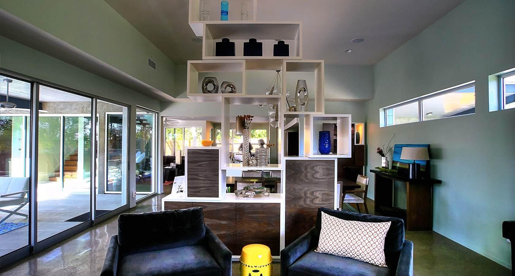 Modern living room with open shelving display, glass doors, and seating.