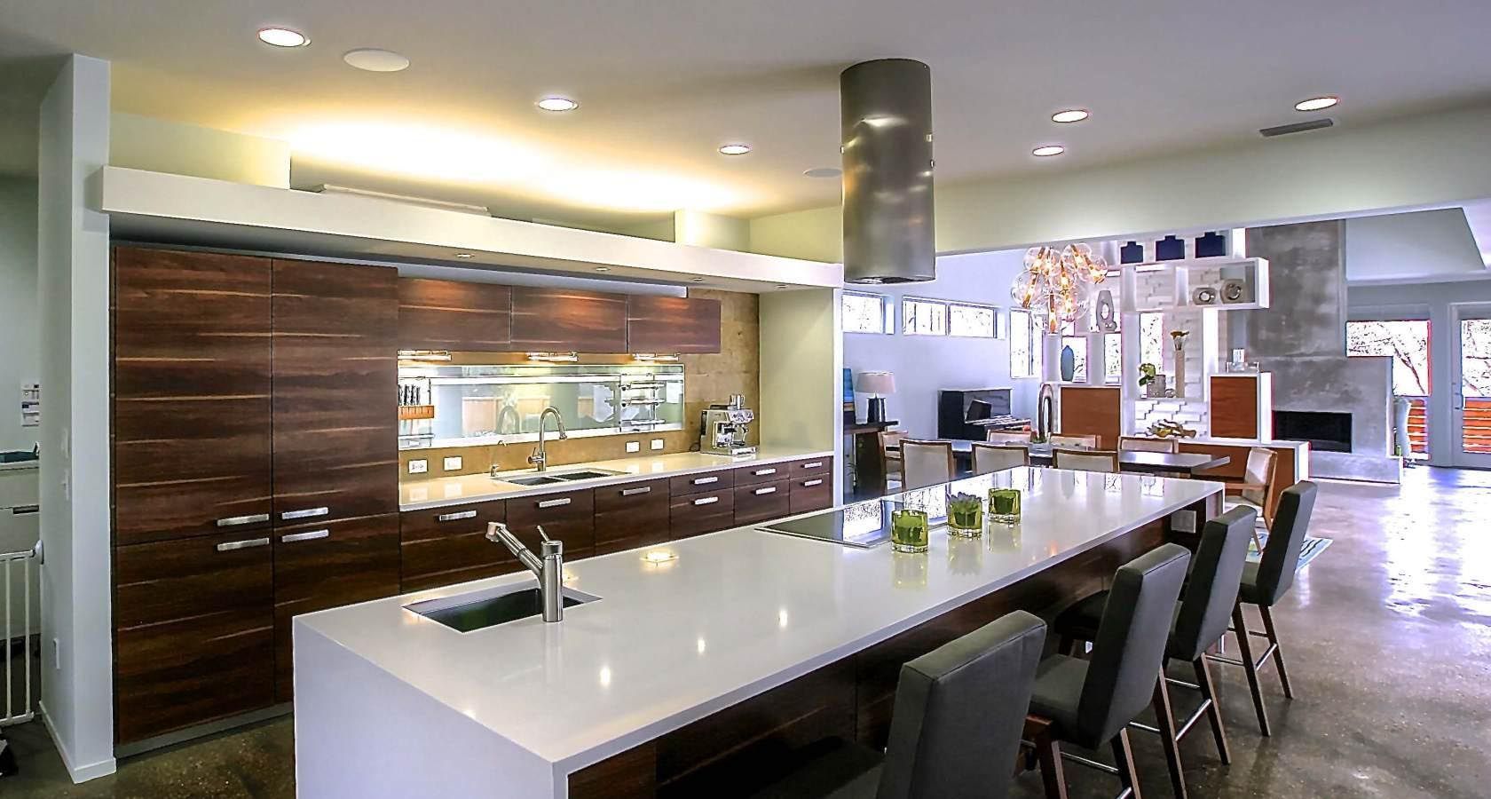 Modern kitchen with large island, wood cabinetry, and stainless steel range hood.