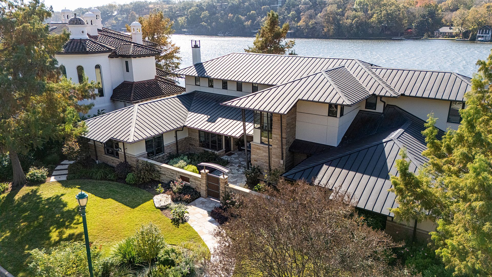 Large house with multiple roof sections near water.
