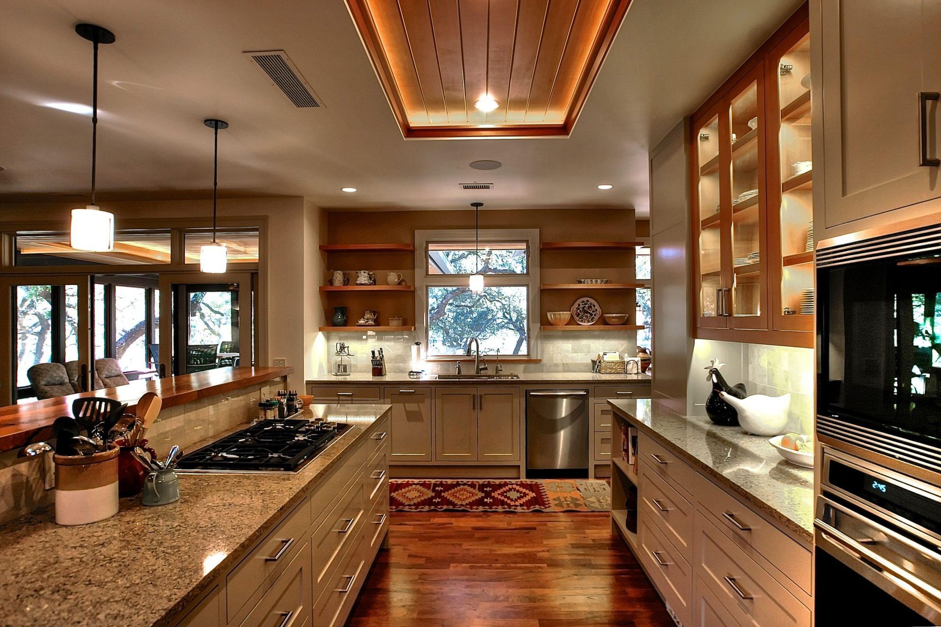 Modern kitchen with wood ceiling, granite countertops, and stainless steel appliances.