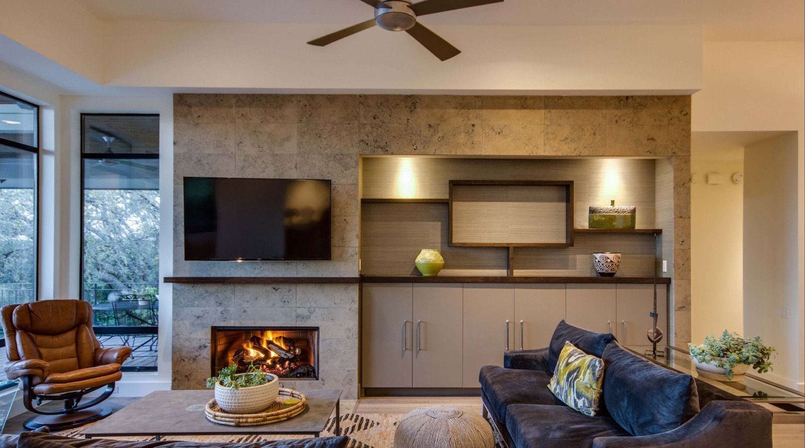 Living room with fireplace, TV, built-in cabinetry, and seating. Beige and gray color scheme.