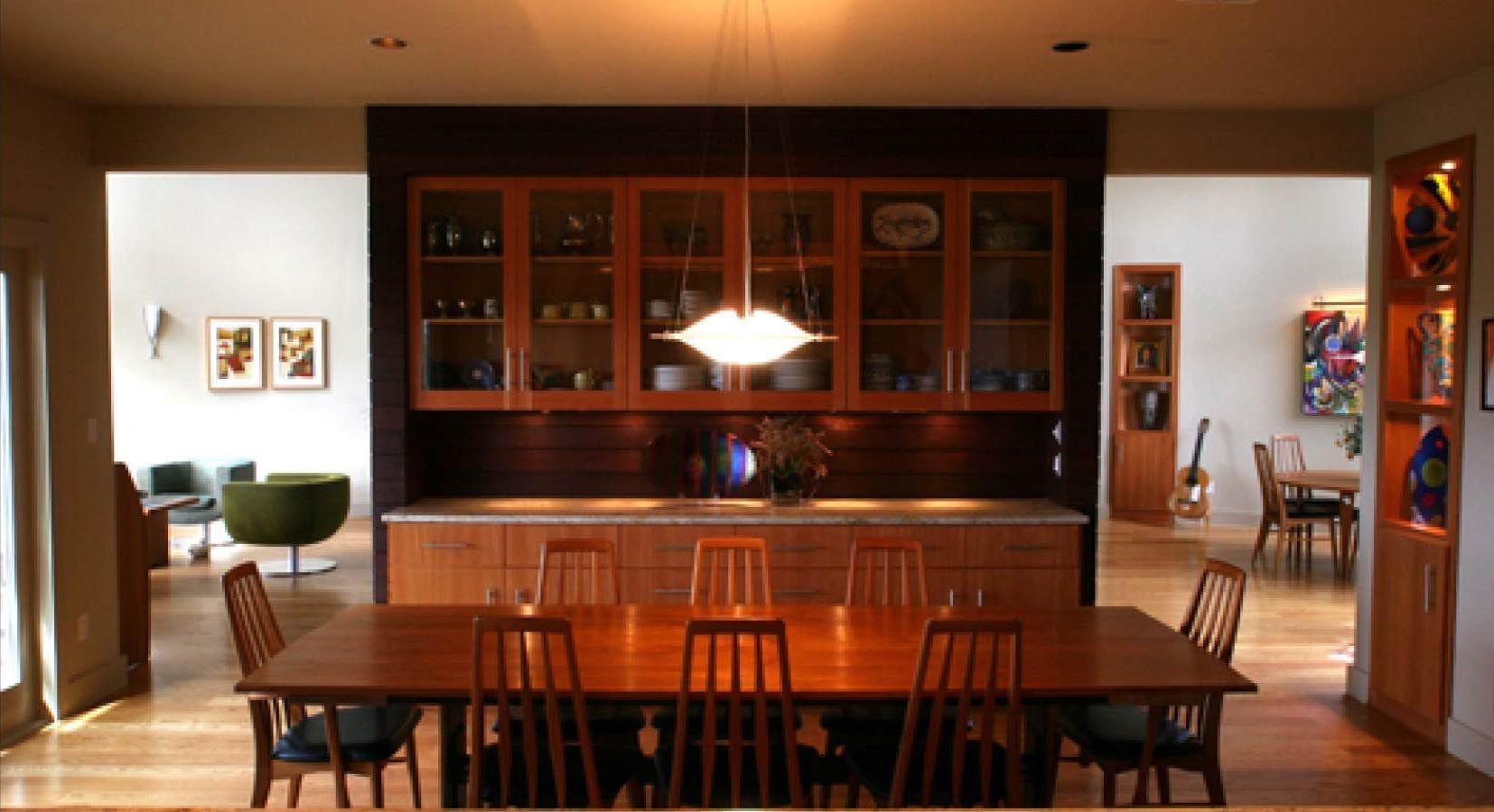 Dining room with wooden table and chairs, built-in cabinet with glass doors, and view to other rooms.