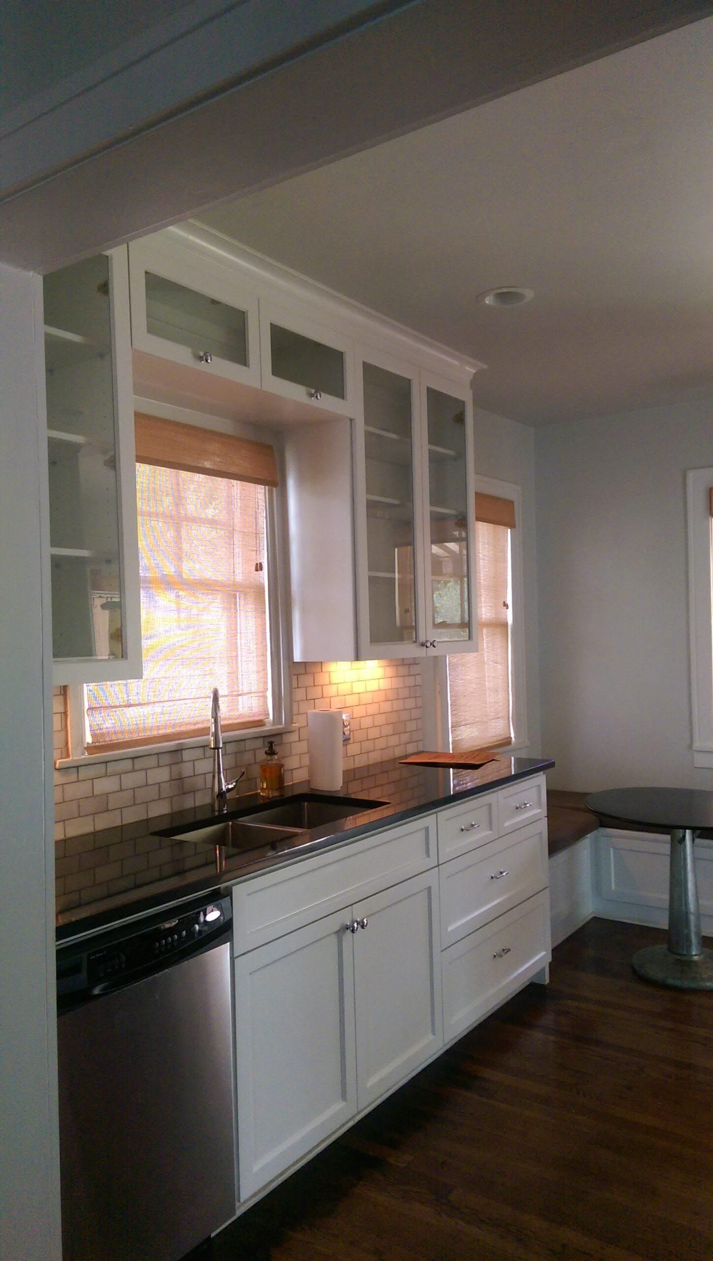 White kitchen cabinets with glass doors, stainless steel appliances, and dark countertop.