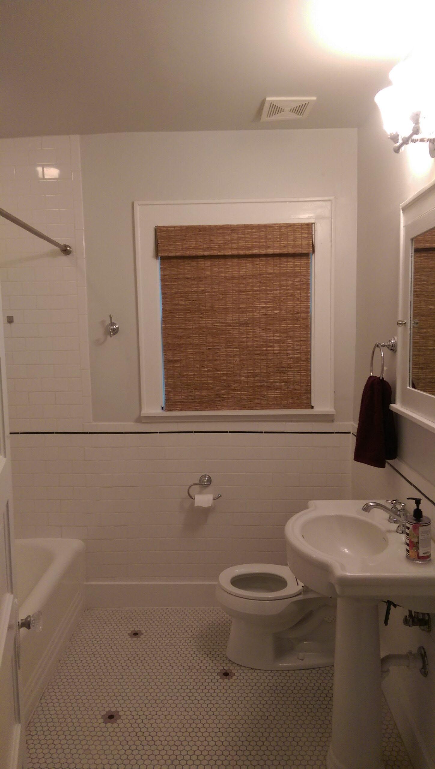 Bathroom with white tile, a window with brown shades, and a pedestal sink.