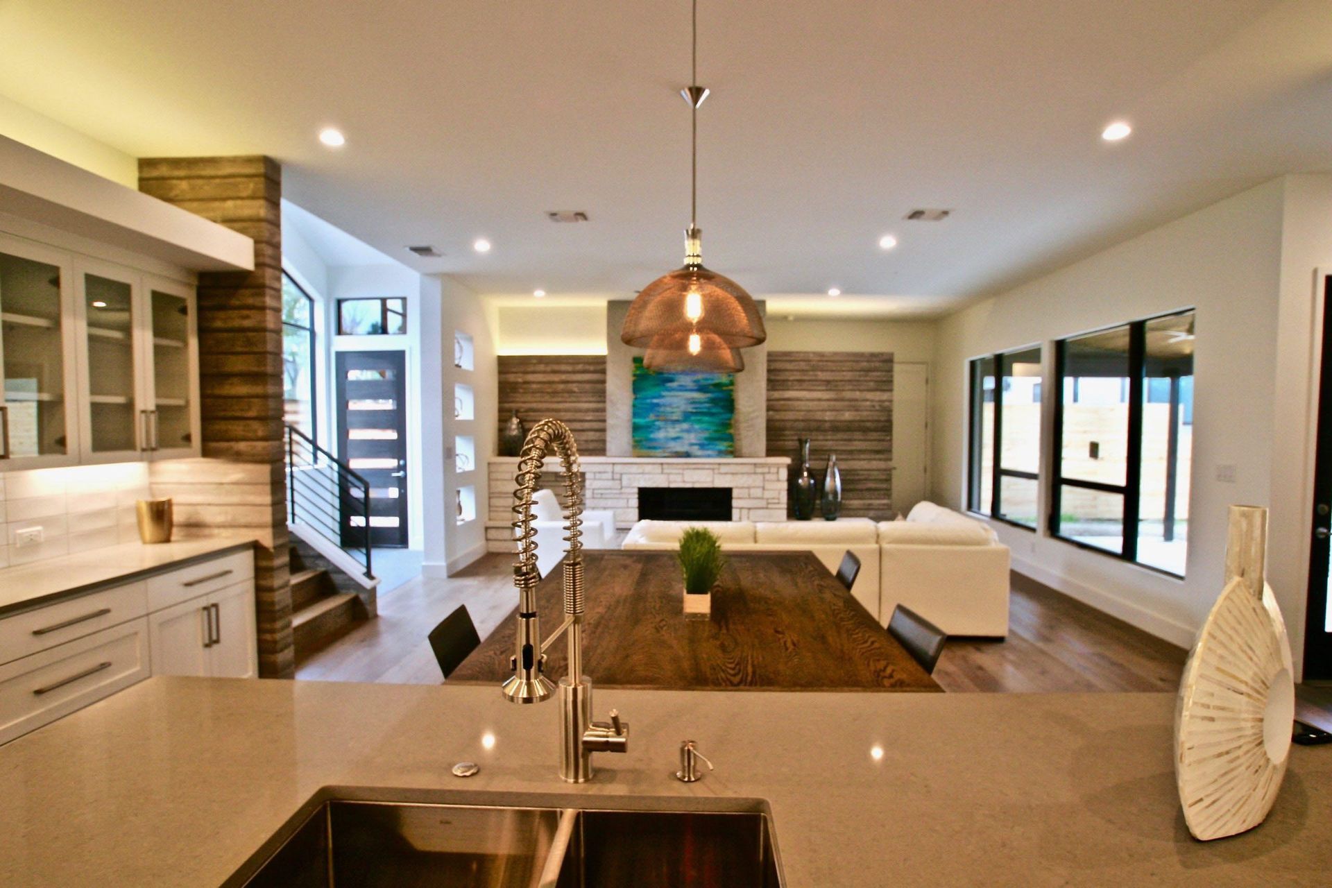 Modern kitchen and living area, featuring a large island, wood accents, and contemporary decor.