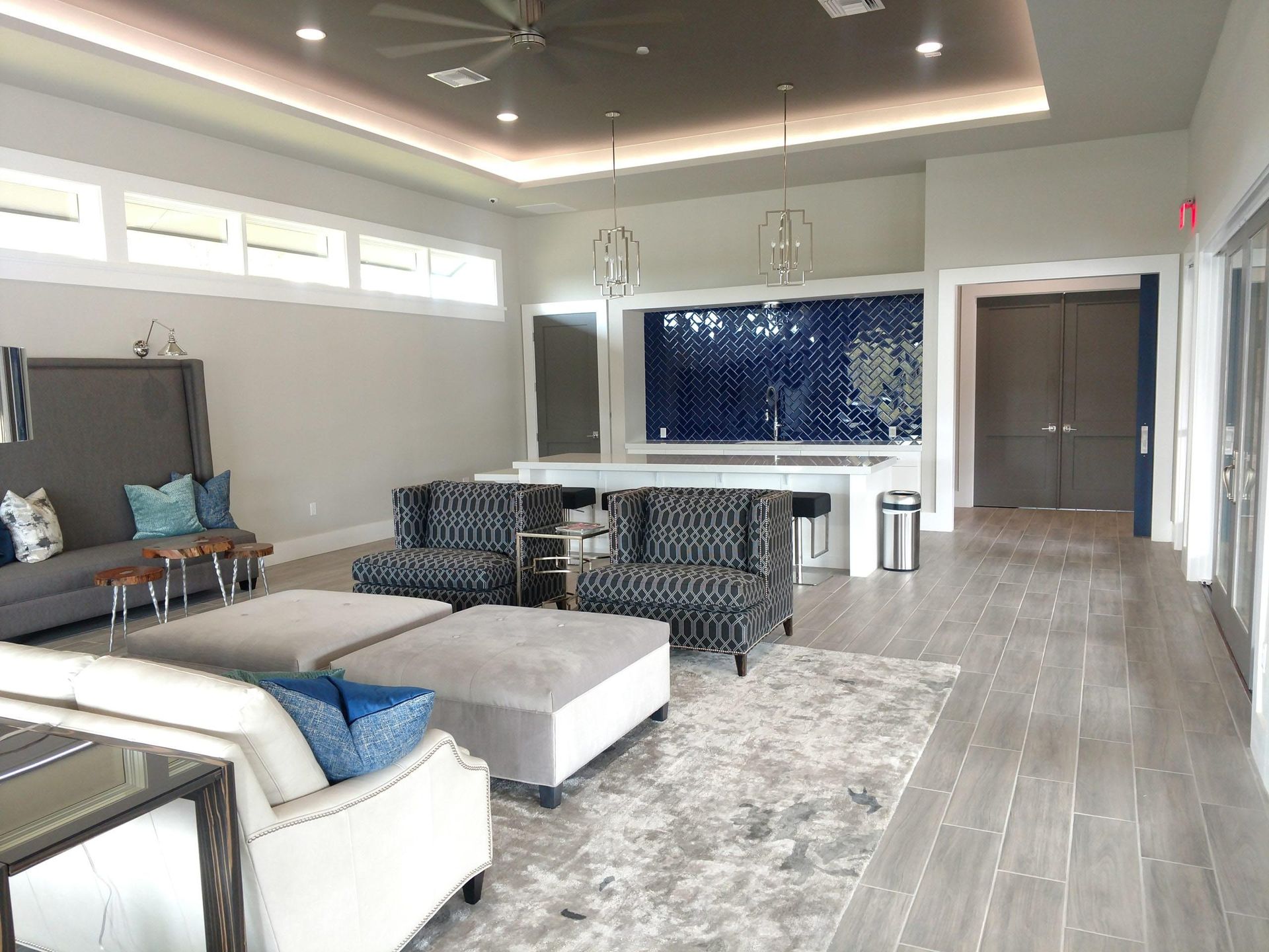 Lounge area with gray walls, seating, and a mosaic tile backsplash. Wooden floors and recessed lighting.