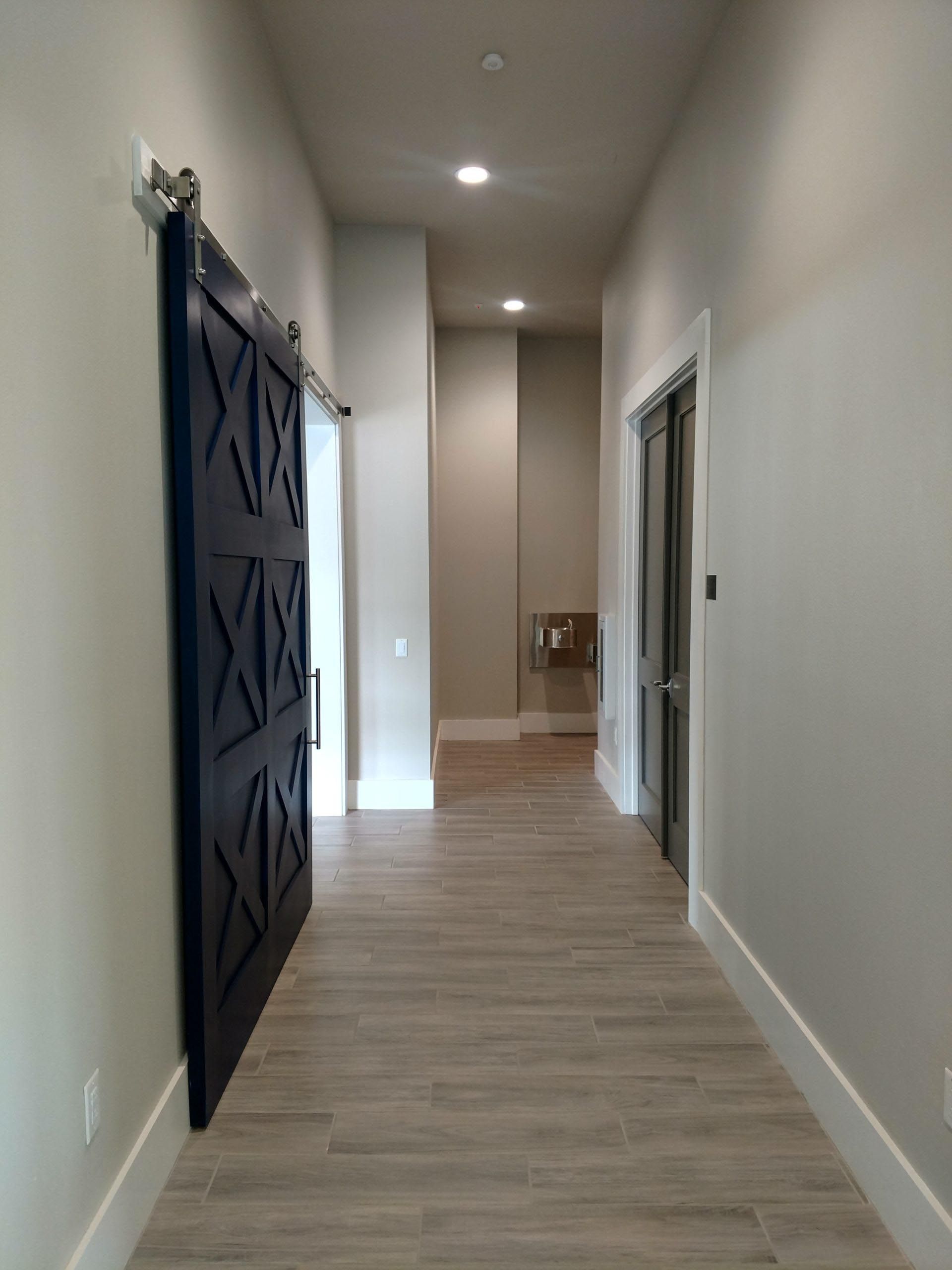 Hallway with wood-look tile flooring, white trim, and a navy barn door on the left side.