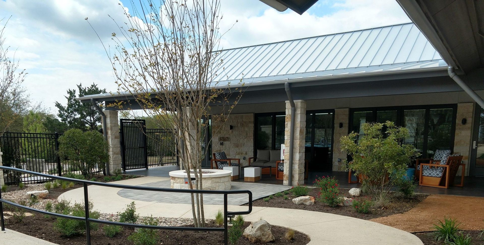 Outdoor patio with seating area, fire pit, and building with metal roof.