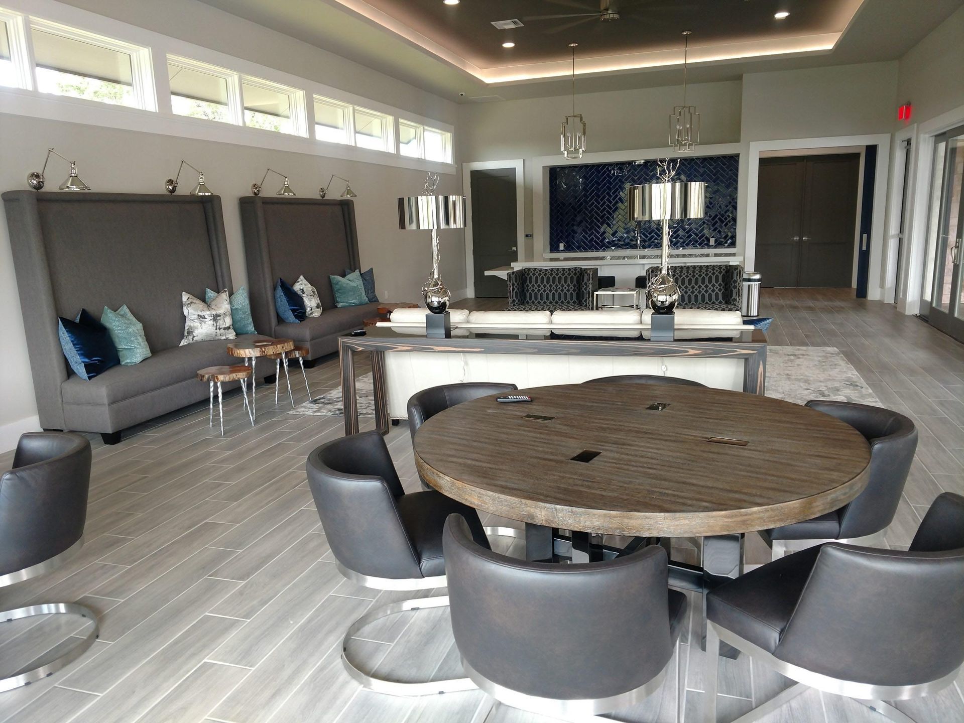 Lounge area with gray seating, round wood table, and blue accent pillows.