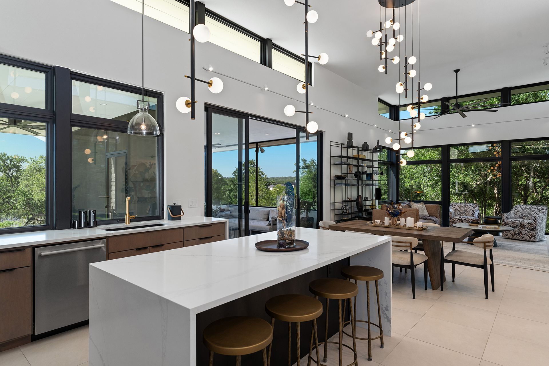 Modern kitchen and dining room with large windows, island, and overhead light fixtures.