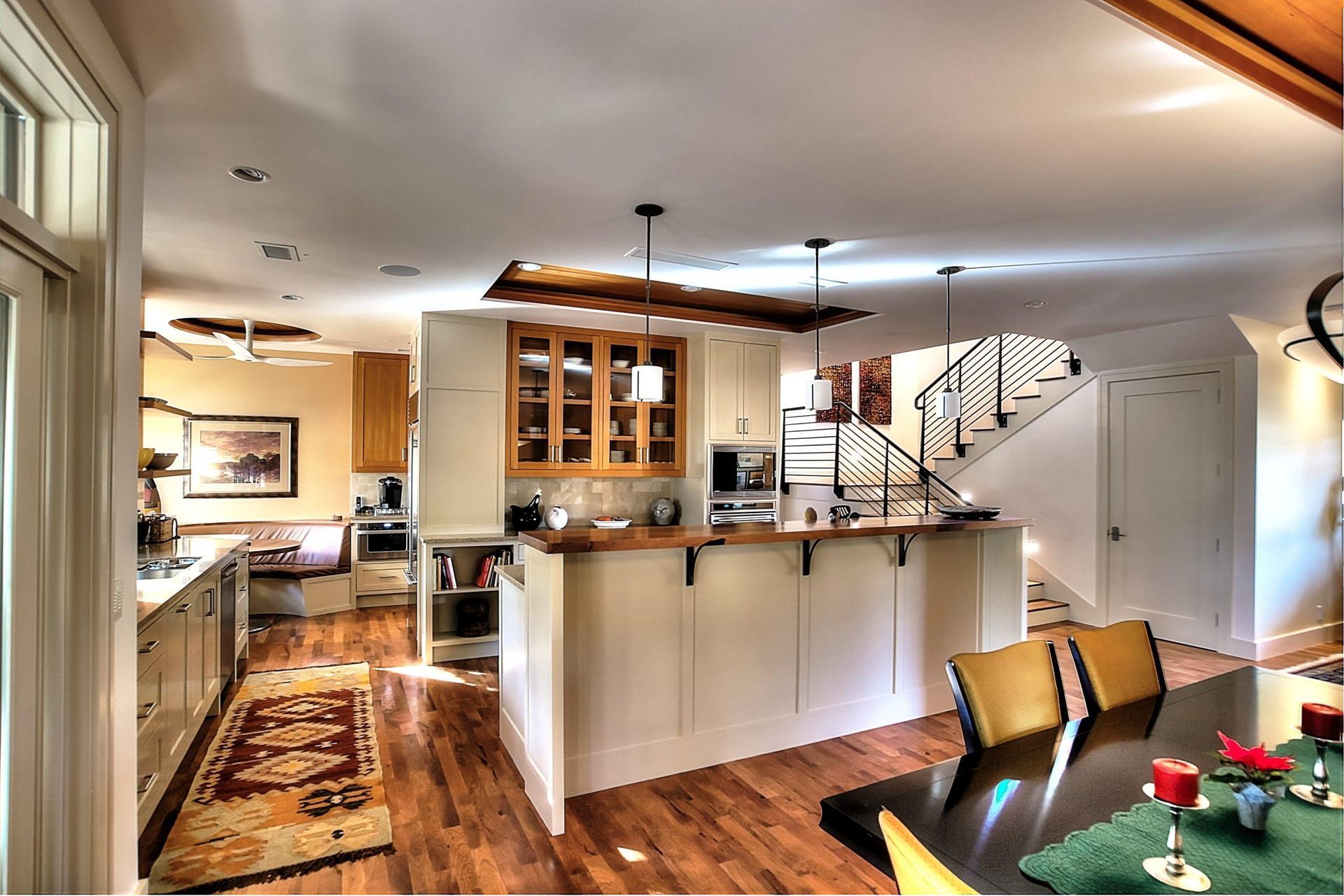 Modern kitchen with white cabinets, wooden countertops, island, and staircase.