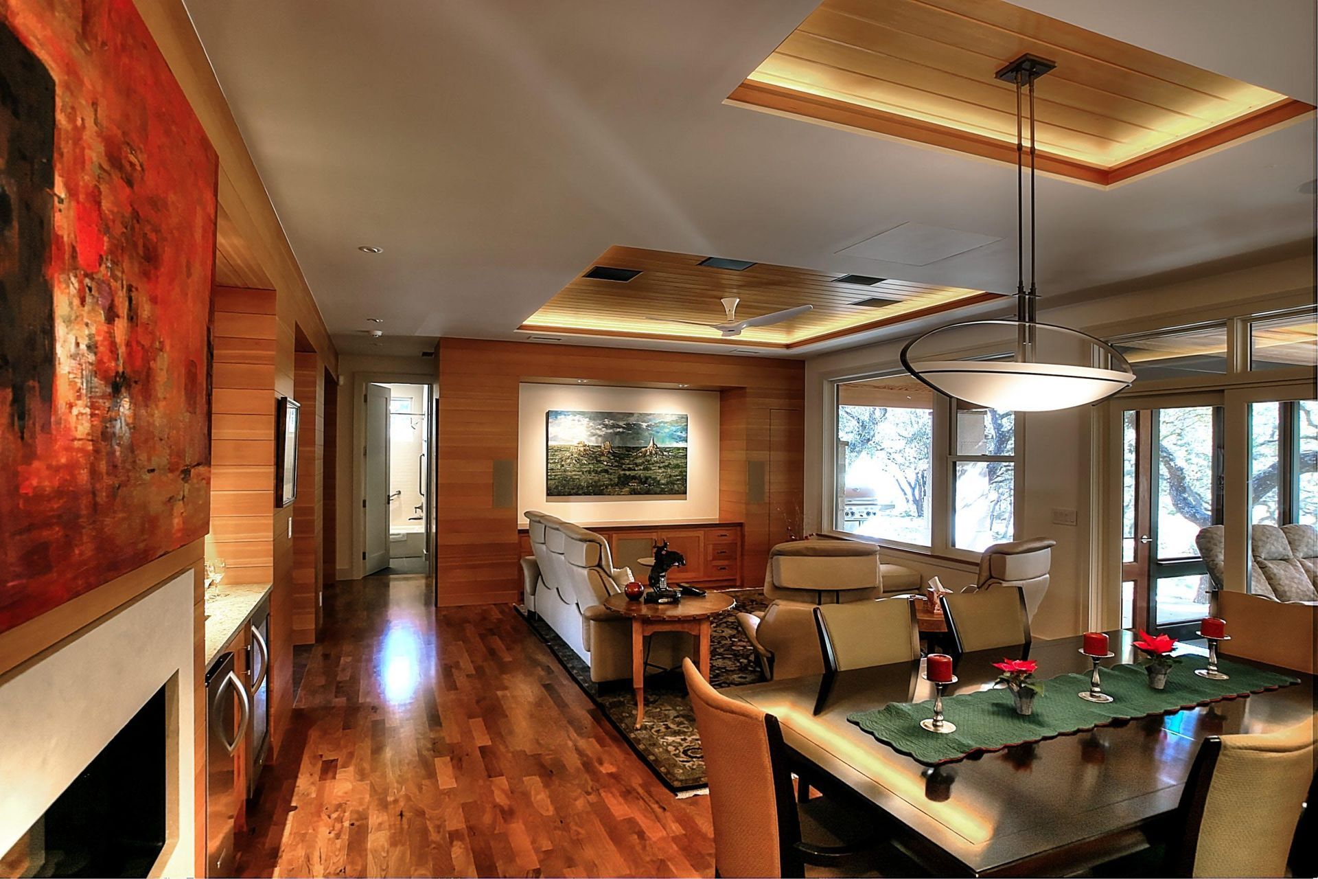 Interior view of a modern living and dining area with hardwood floors, artwork, and natural light.
