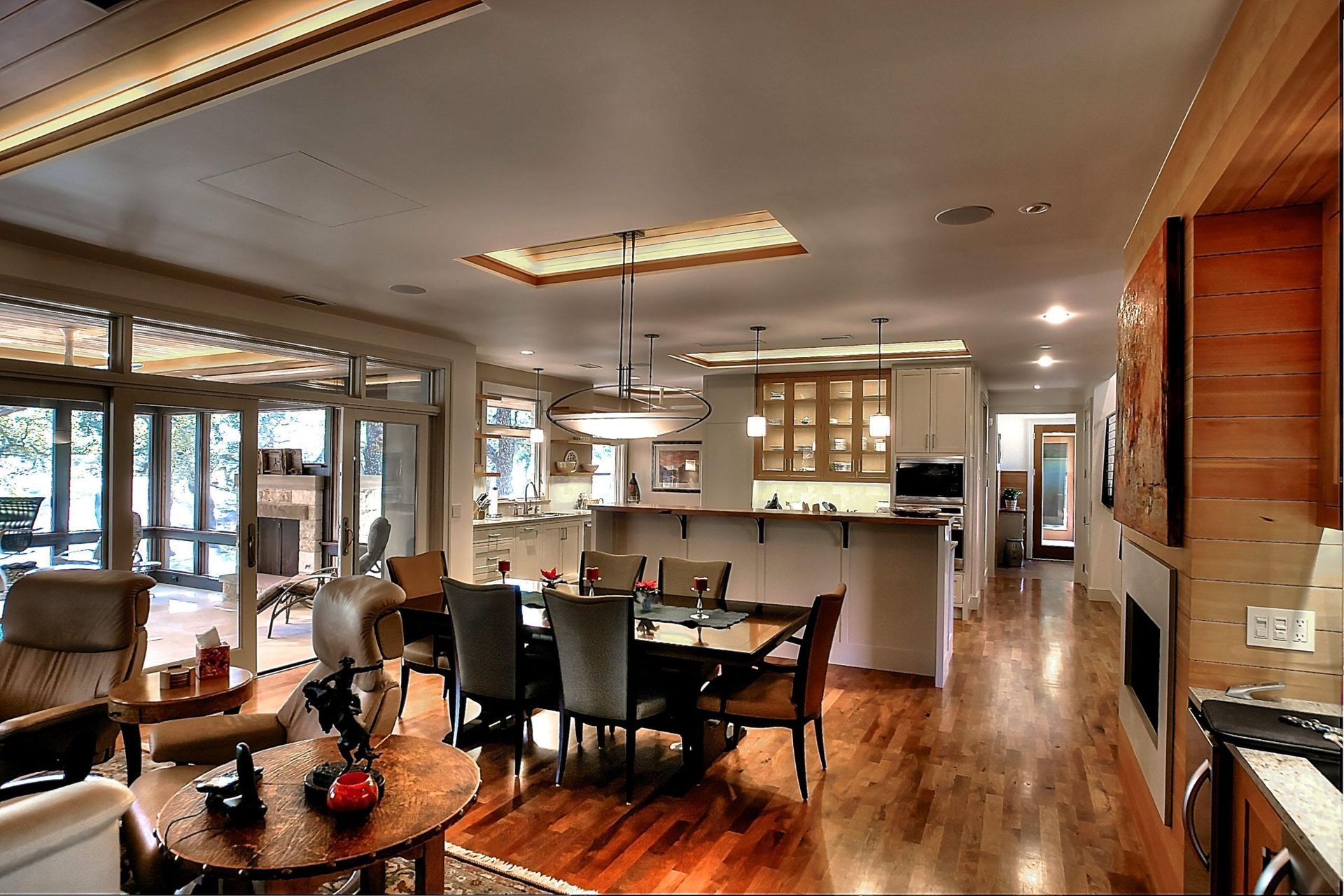 Spacious modern living room with dining area, kitchen, and fireplace. Hardwood floors, natural light.