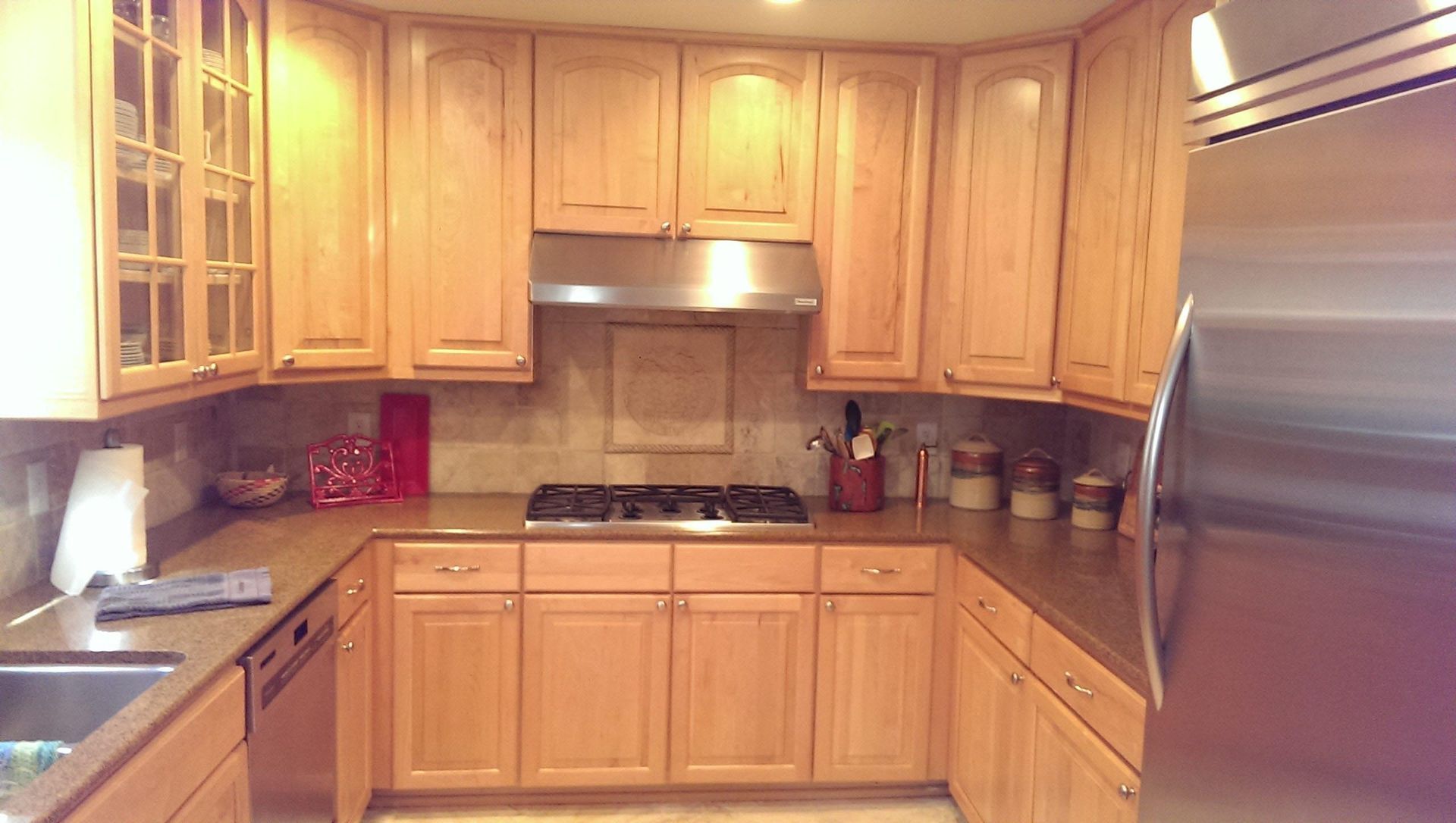 U-shaped kitchen with light wood cabinets, stainless steel appliances, and a gas stovetop.