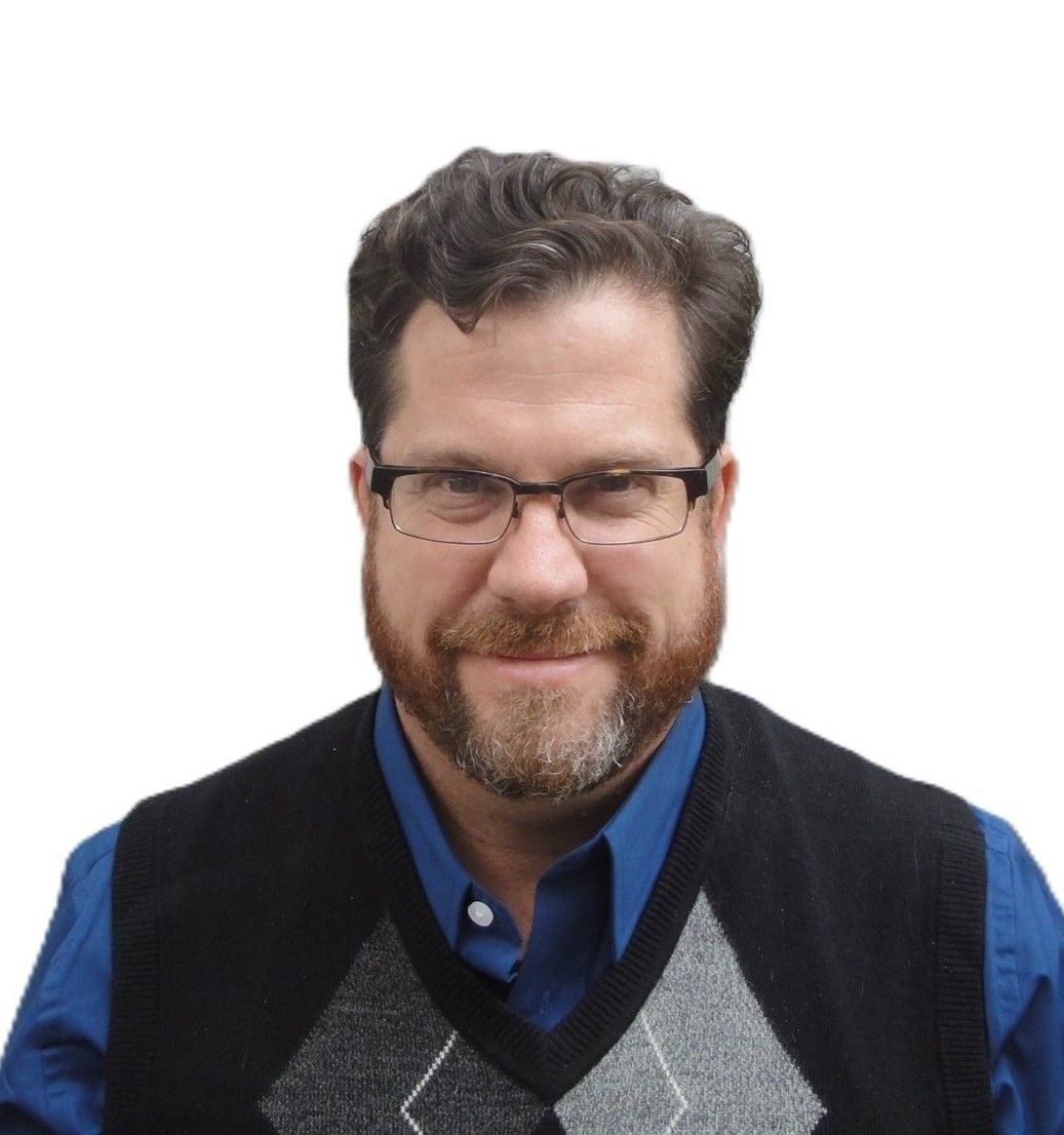 A man with a beard and glasses is smiling for the camera.