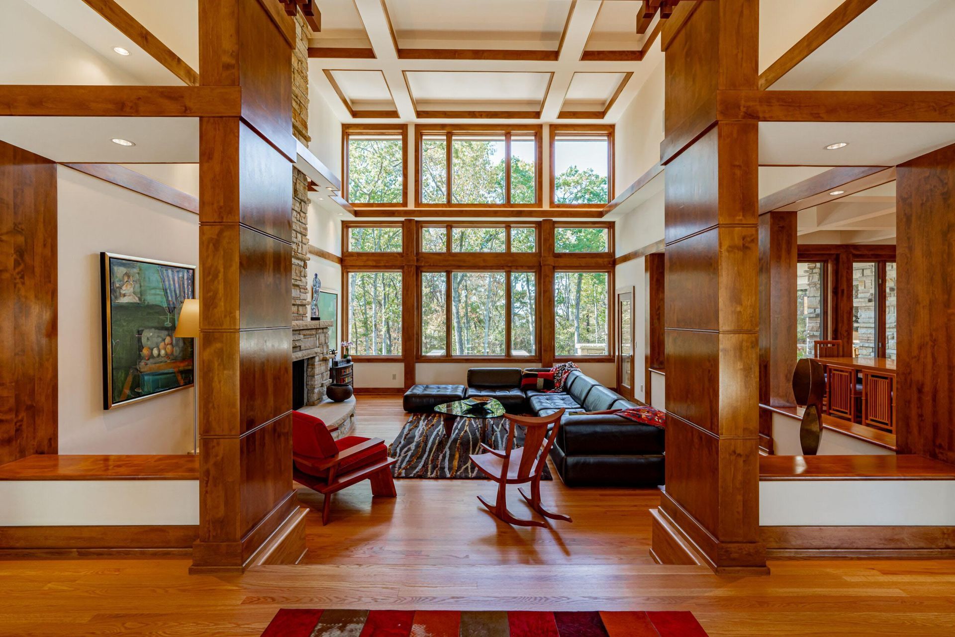 Living room with wooden beams, large windows, and colorful furniture.