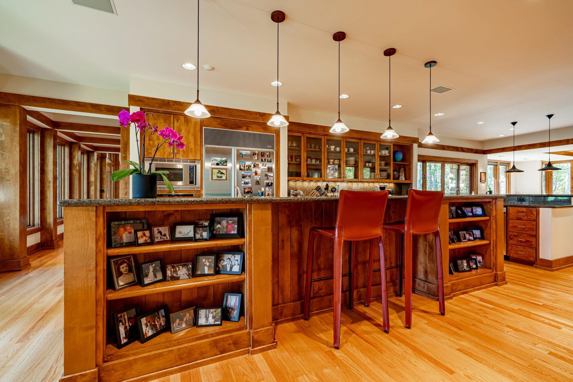 Kitchen with wooden cabinets, island with stools, and light fixtures.