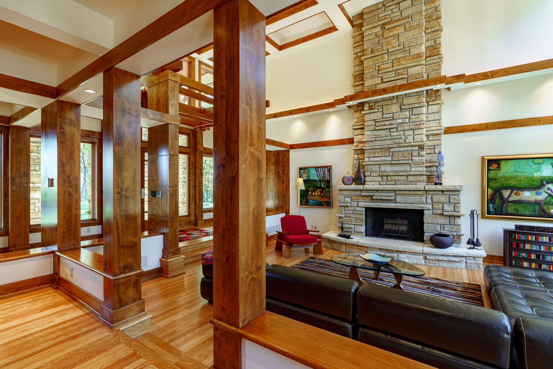 Spacious living room with stone fireplace, wooden beams, hardwood floors, and a leather sofa.