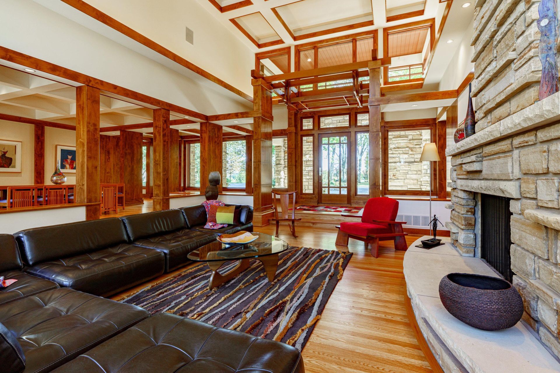 Living room with wooden beams, black leather sectional, fireplace, and glass coffee table.