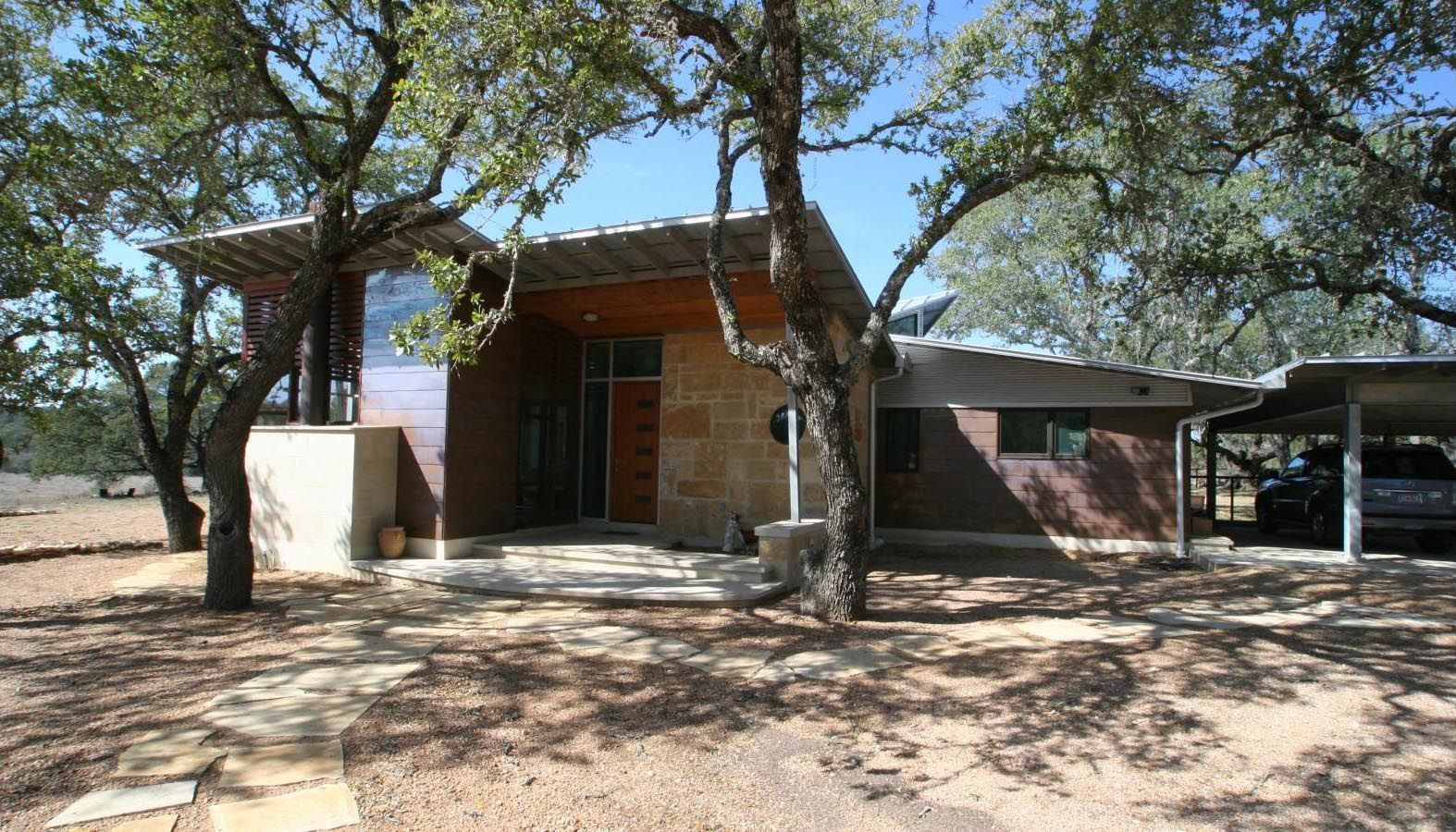 Modern, single-story home with carport, brown brick exterior, and stone entrance.