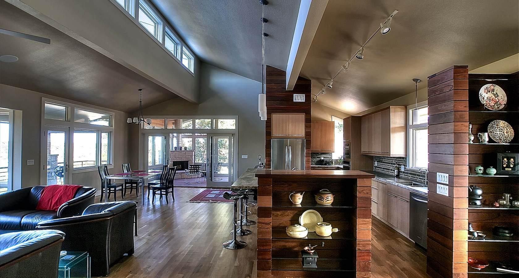 Spacious living room and kitchen; wooden floors, high ceilings, large windows, and a built-in display shelf.