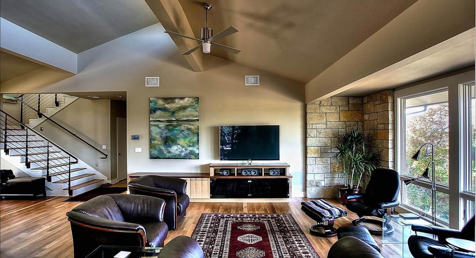 Living room with leather furniture, large windows, and a staircase.