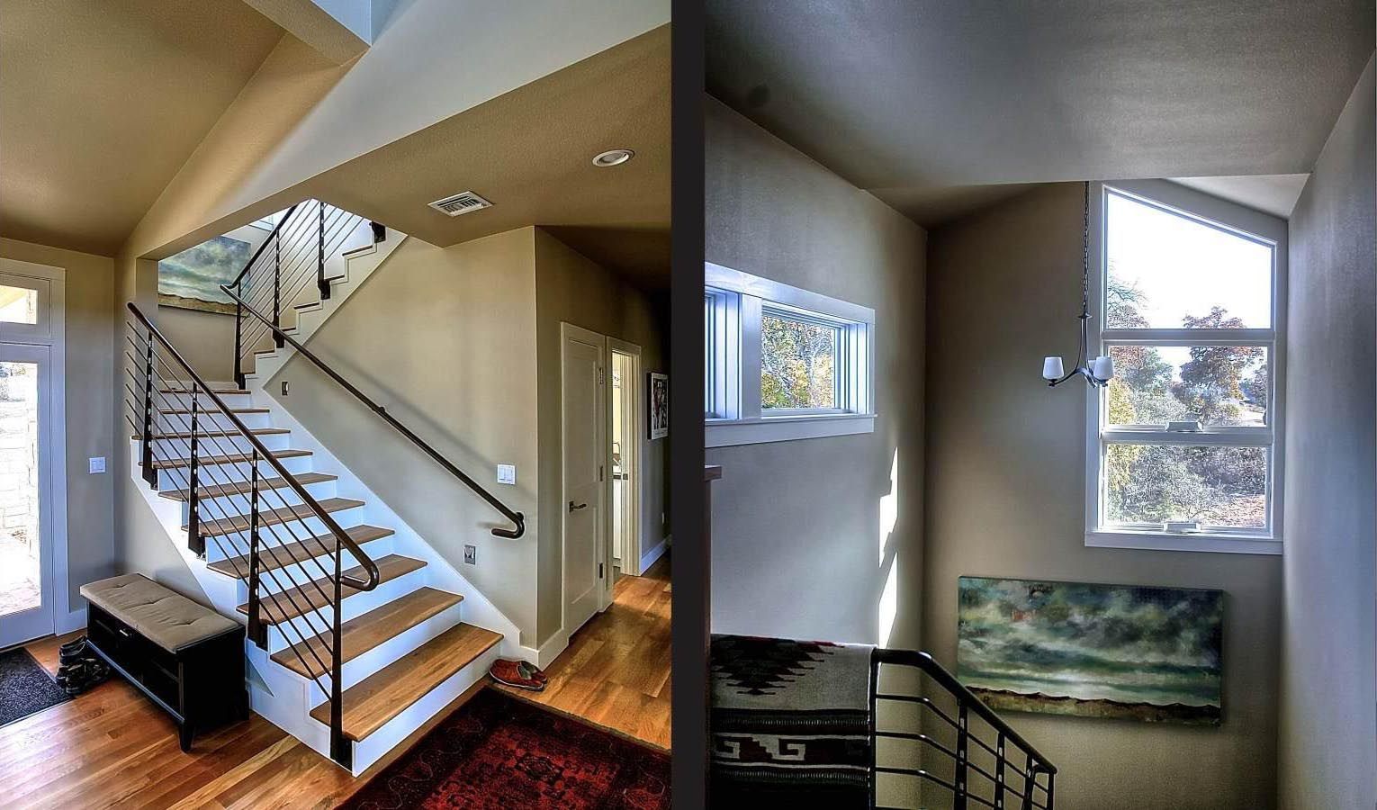 Interior staircase with wood steps, black railings, and a painting under a window.