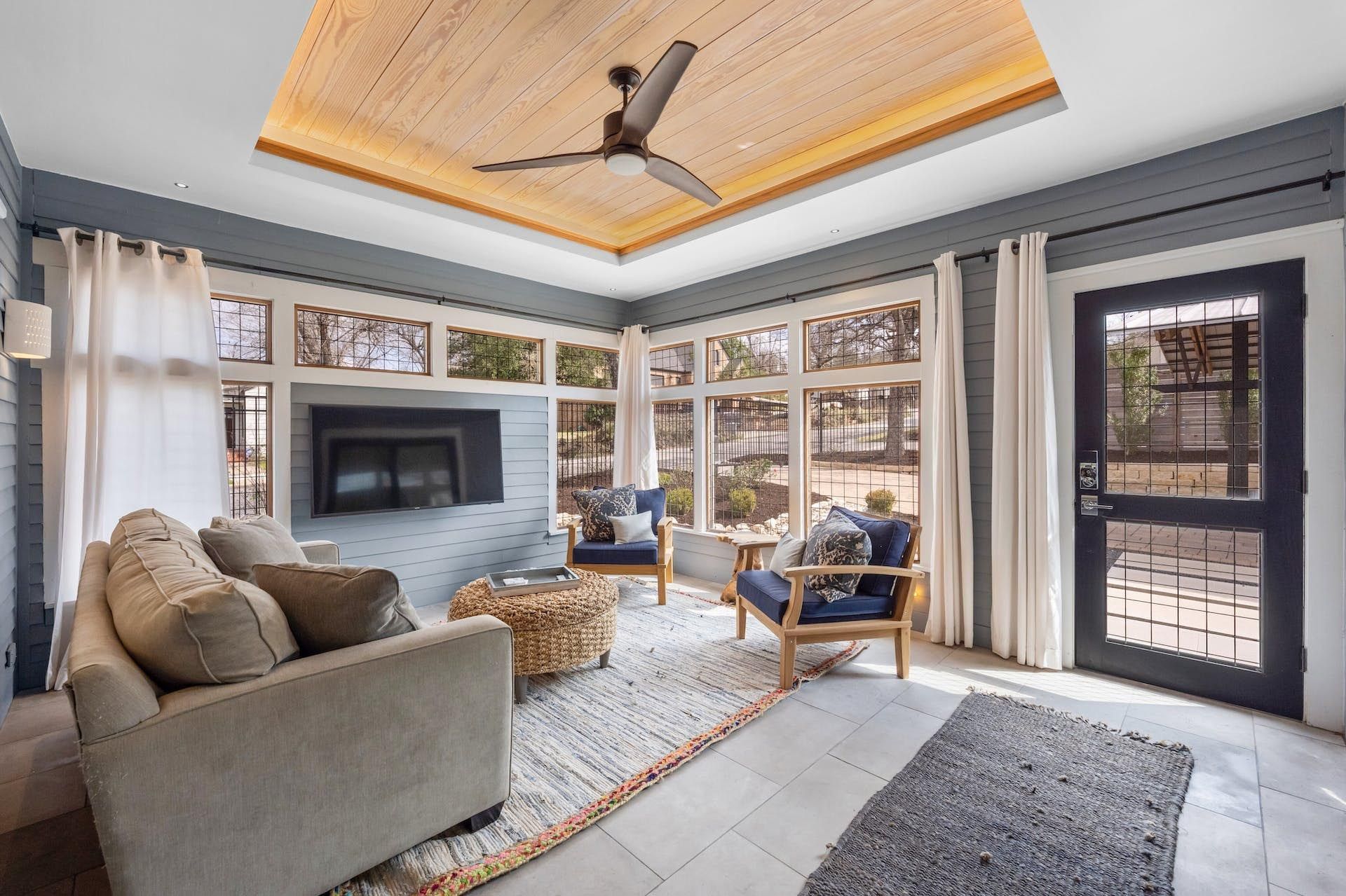 Sunroom with light wood ceiling, blue walls, a fireplace, and various seating options.