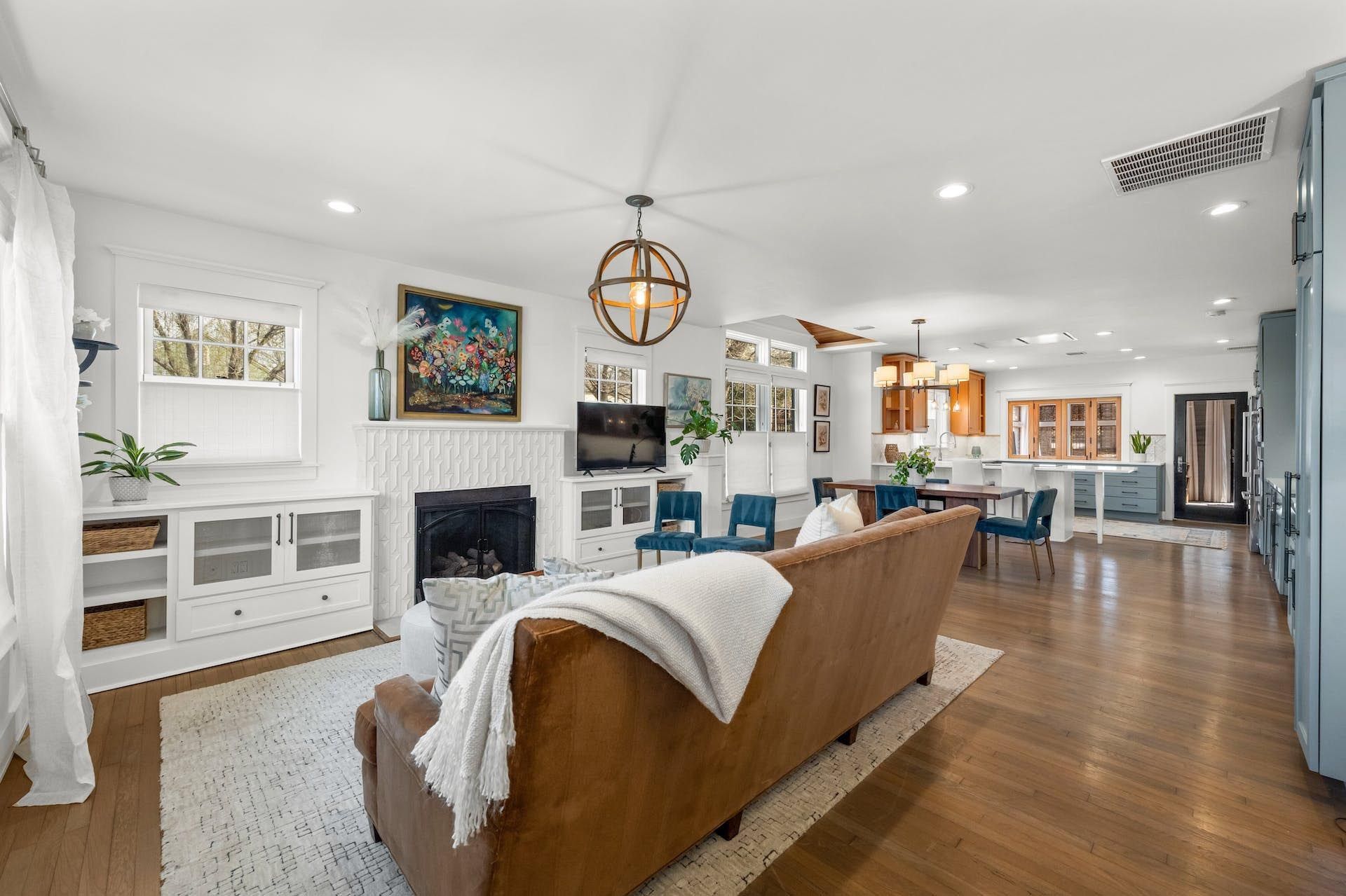 Spacious living room with brown leather sofa, fireplace, and open floor plan with dining area and kitchen.