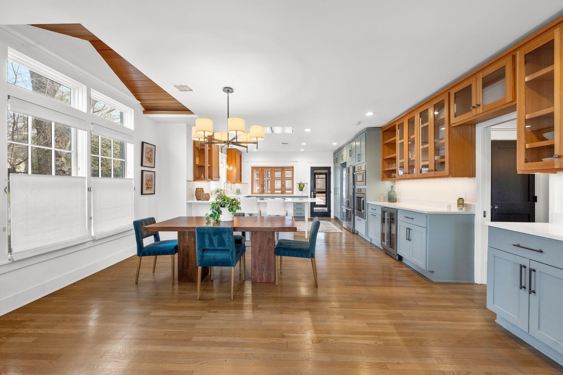 Spacious kitchen with wood floors, blue cabinets, and a long dining table.