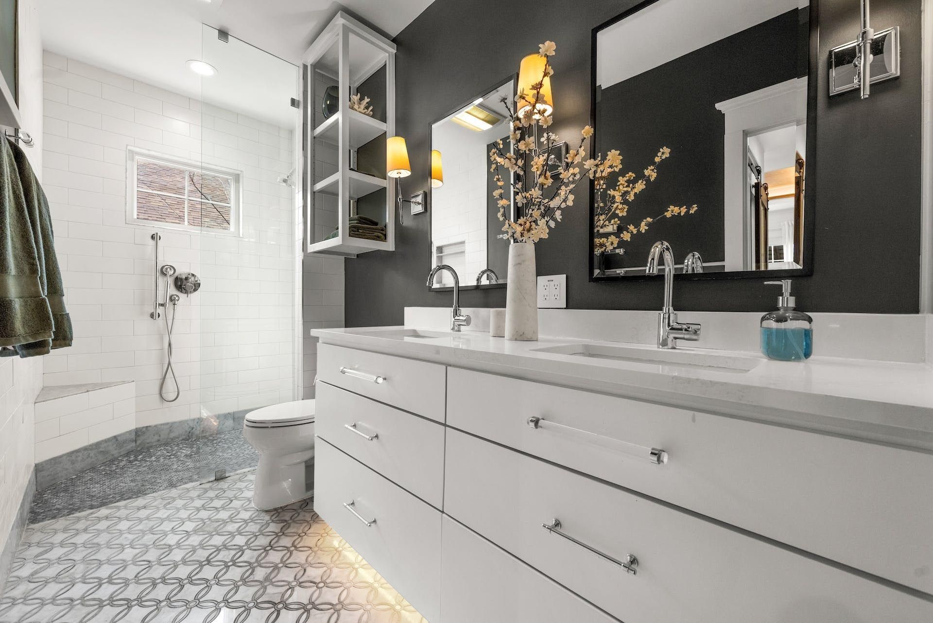 Modern bathroom with white and gray color scheme, featuring a double vanity, shower, and decorative accents.