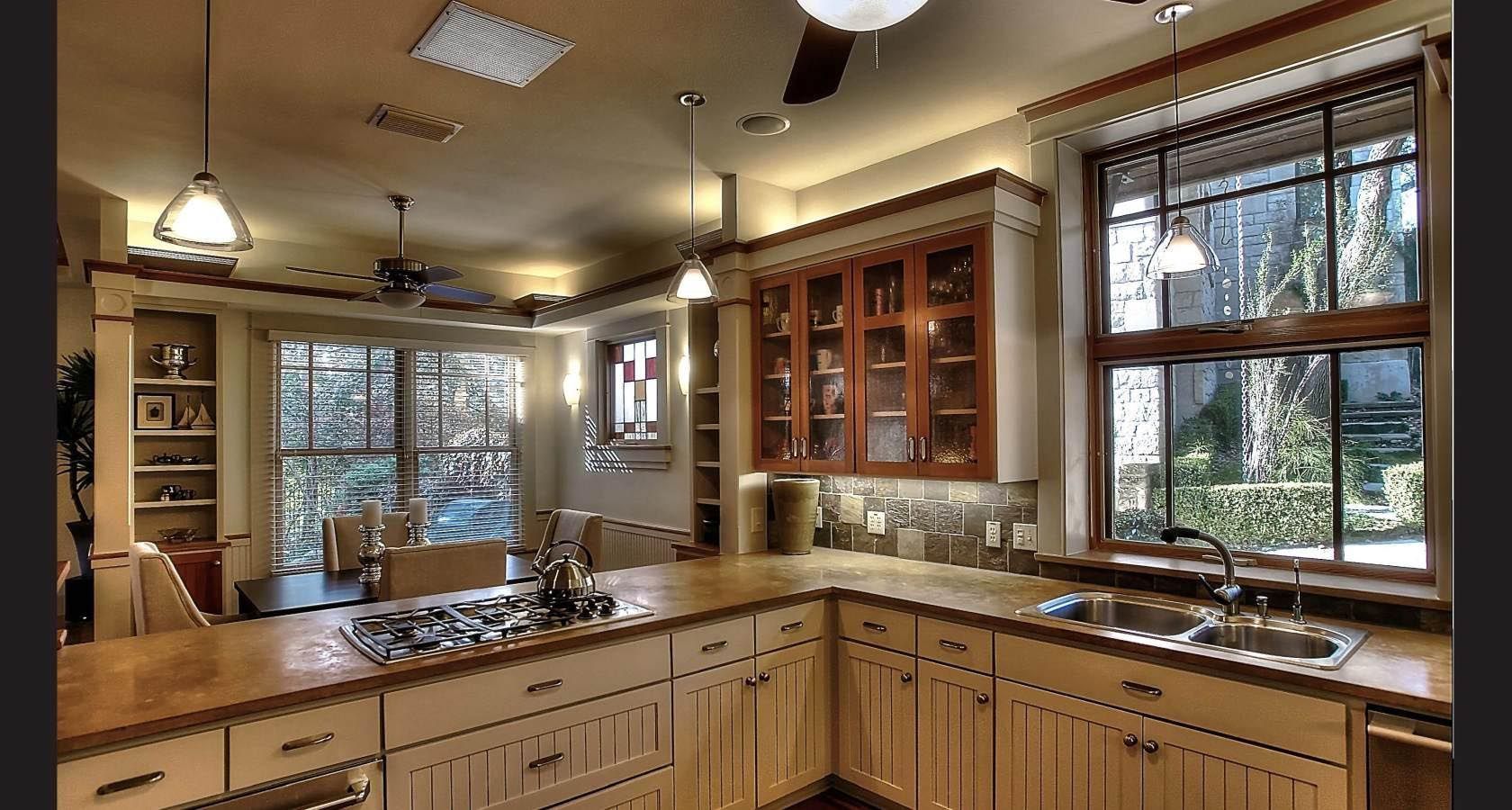 Kitchen with light wood cabinets, countertop, and window with view of trees.