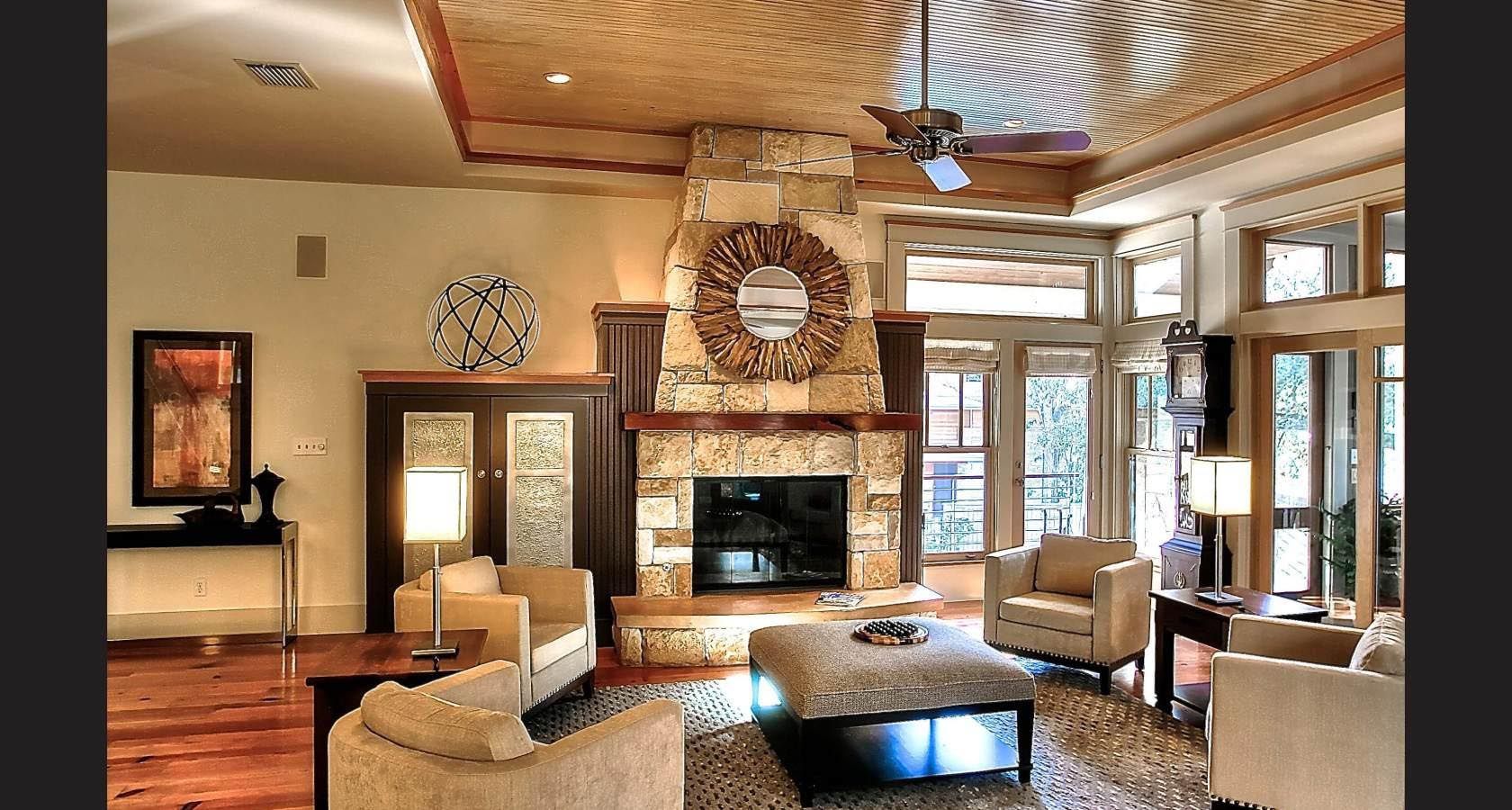 Living room with stone fireplace, wood ceiling, and armchairs.