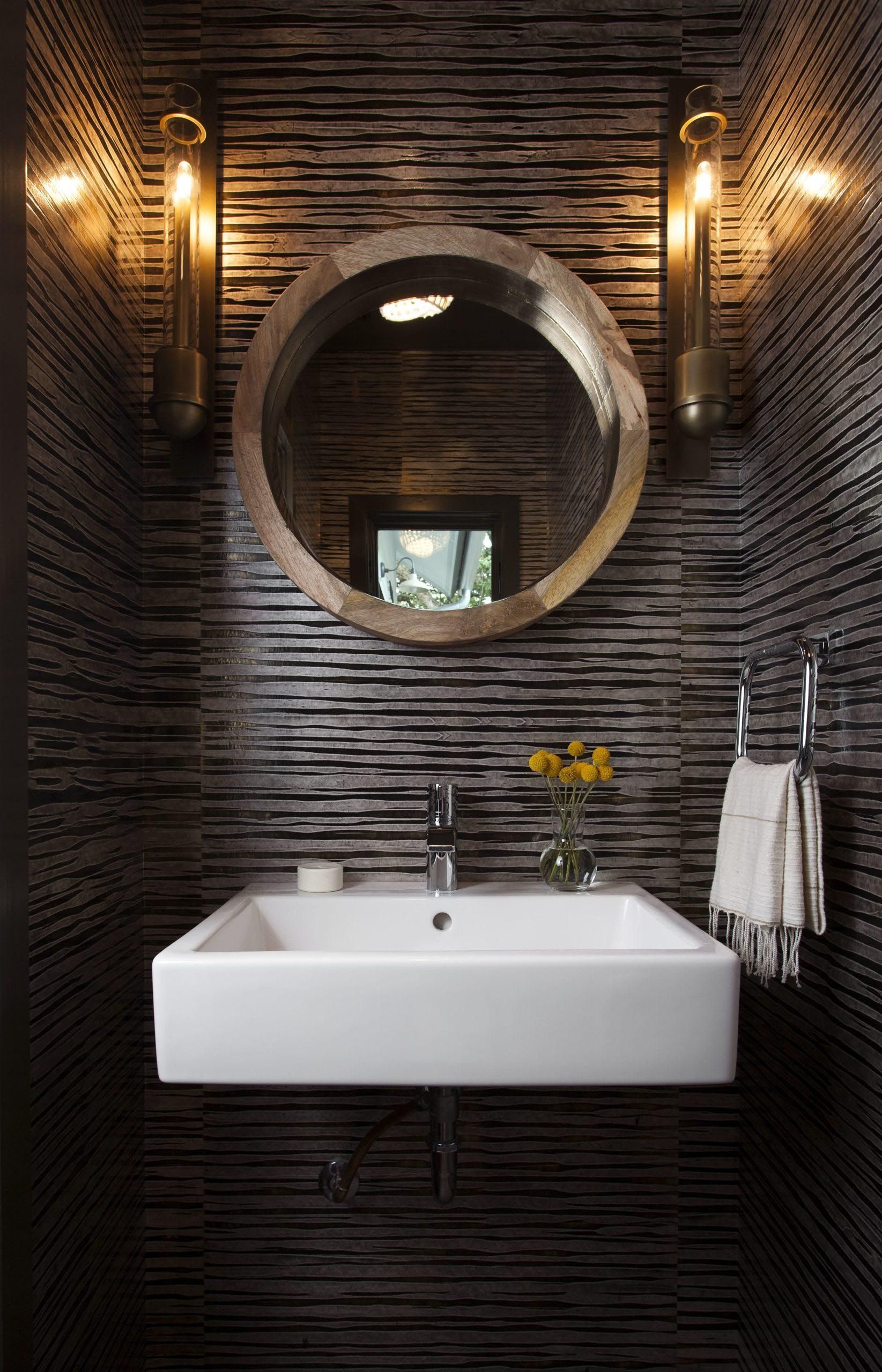 Small bathroom with a white sink, round mirror, and textured dark gray walls.