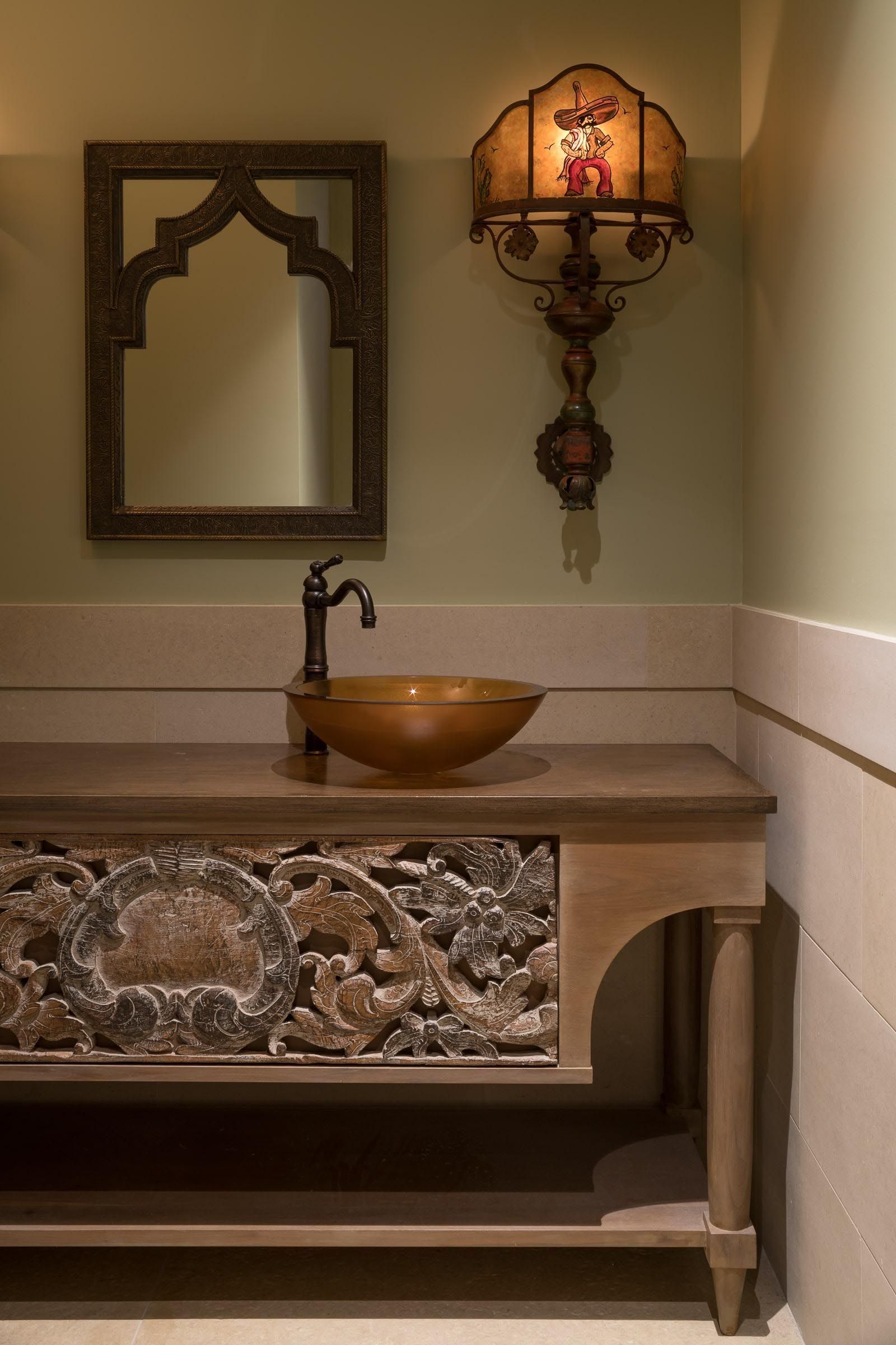 Bathroom with ornate vanity, carved details, vessel sink, decorative mirror, and wall sconce.