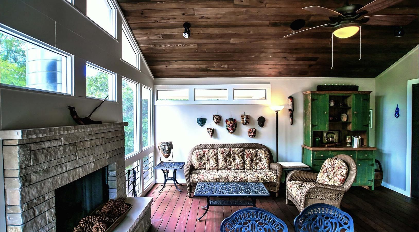 Living room with stone fireplace, wooden ceiling, and eclectic furnishings.
