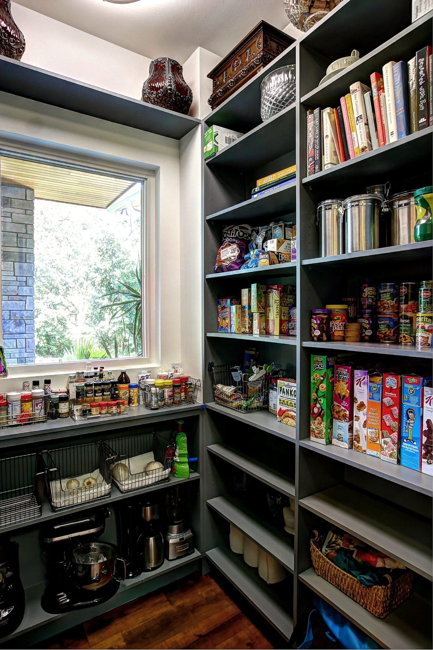 Pantry with gray shelves filled with food items, window view, and a coffee station.